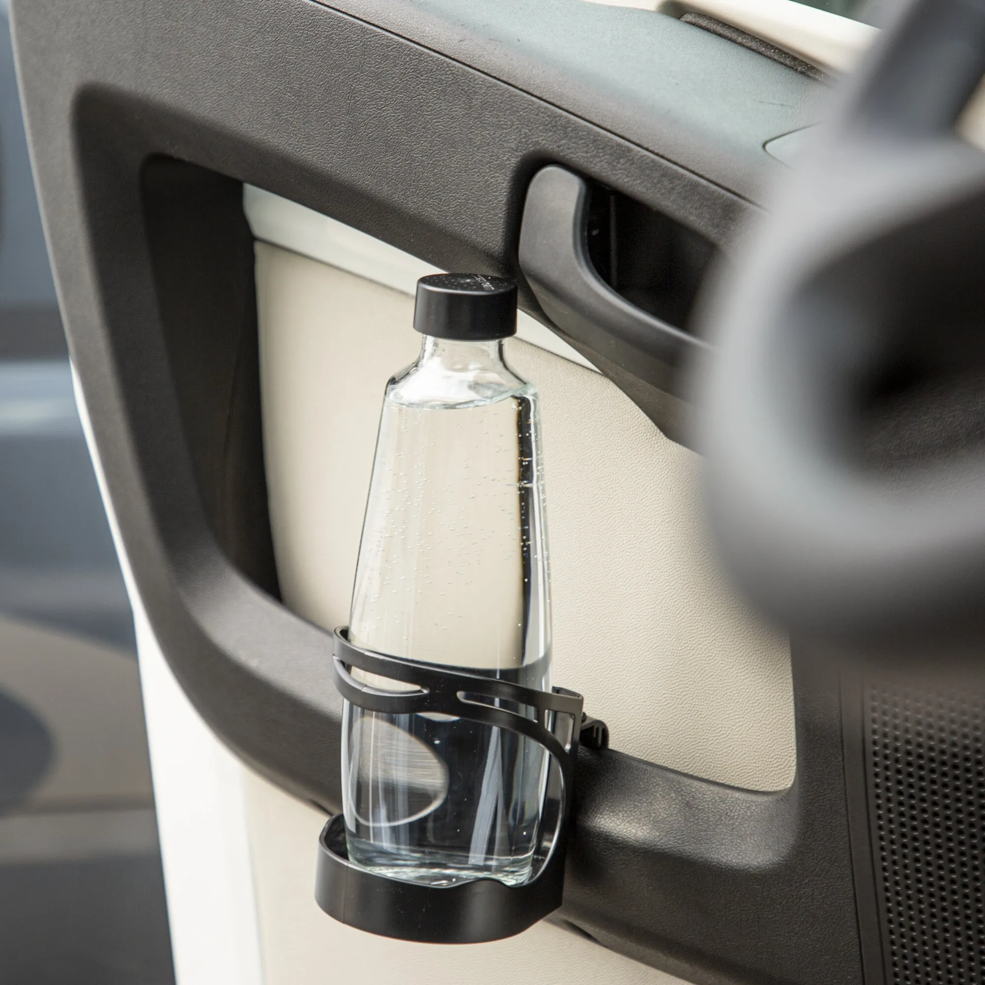 Schwarzer Getränkehalter Bottle Butler an einer Fahrzeugtür mit eingesetzter transparenter Glasflasche mit schwarzem Verschluss
