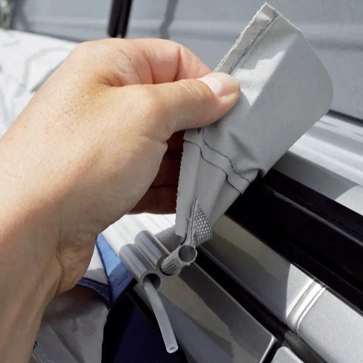 Hand hält einen grauen Verbindungskeder mit Schlaufe an einer Führungsschiene eines Vorzelts 
