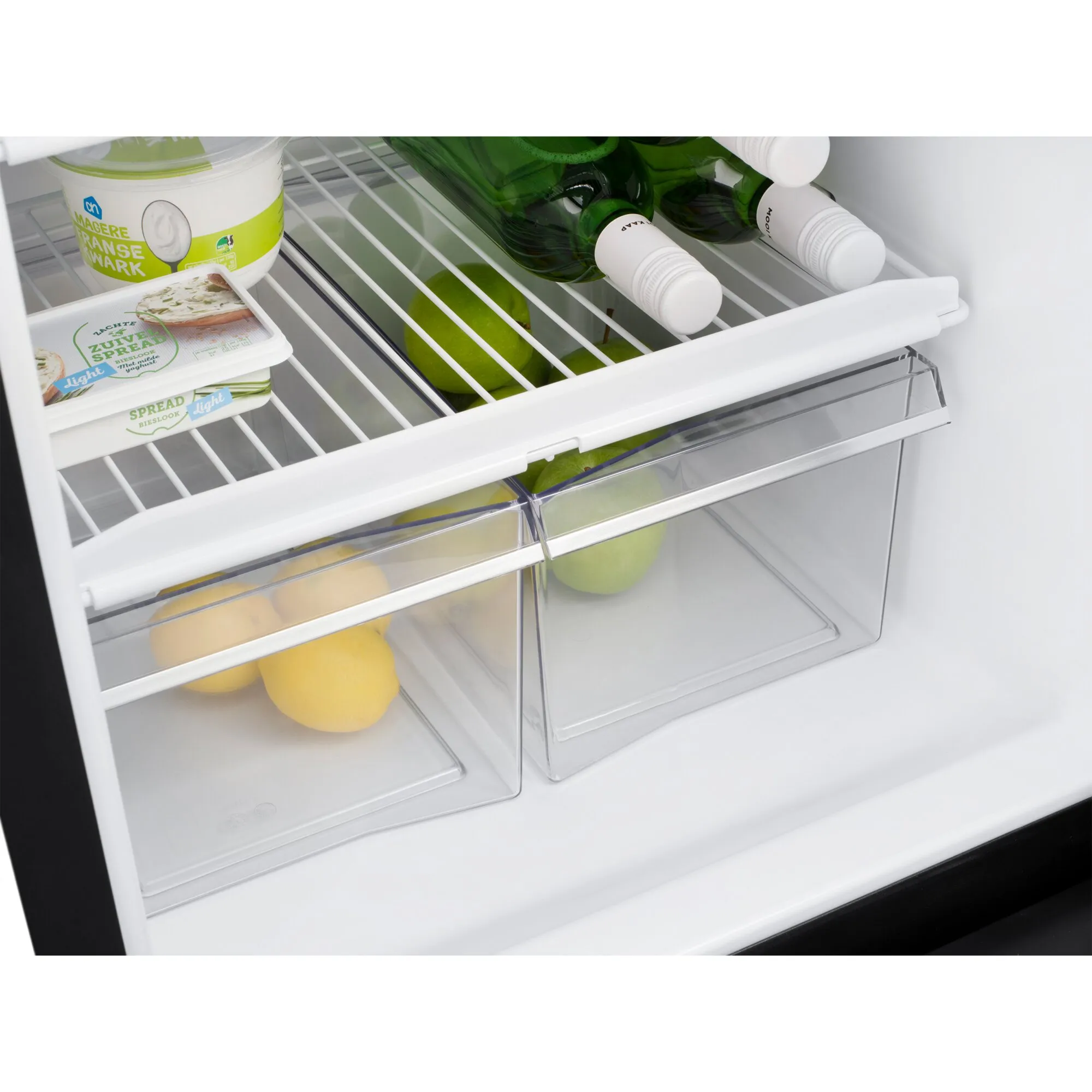 Innenansicht des weißen Kühlschranks T2175 mit Drahtrost, zwei transparenten Gemüsefächern, Getränkeflaschen, Joghurt, Aufstrich und Obst