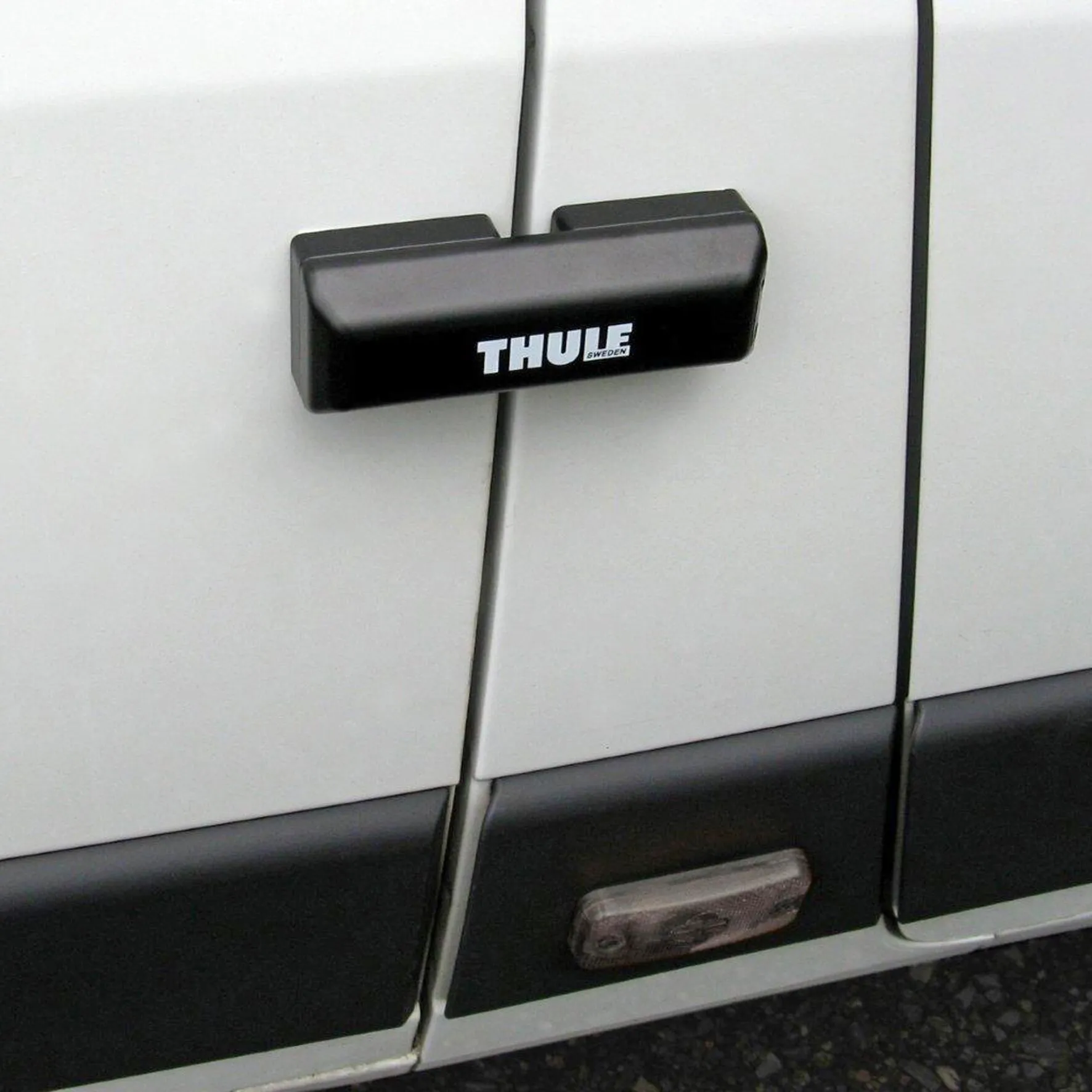 Schwarze Thule Van Lock Türverriegelung an den geschlossenen Hecktüren eines weißen Vans montiert