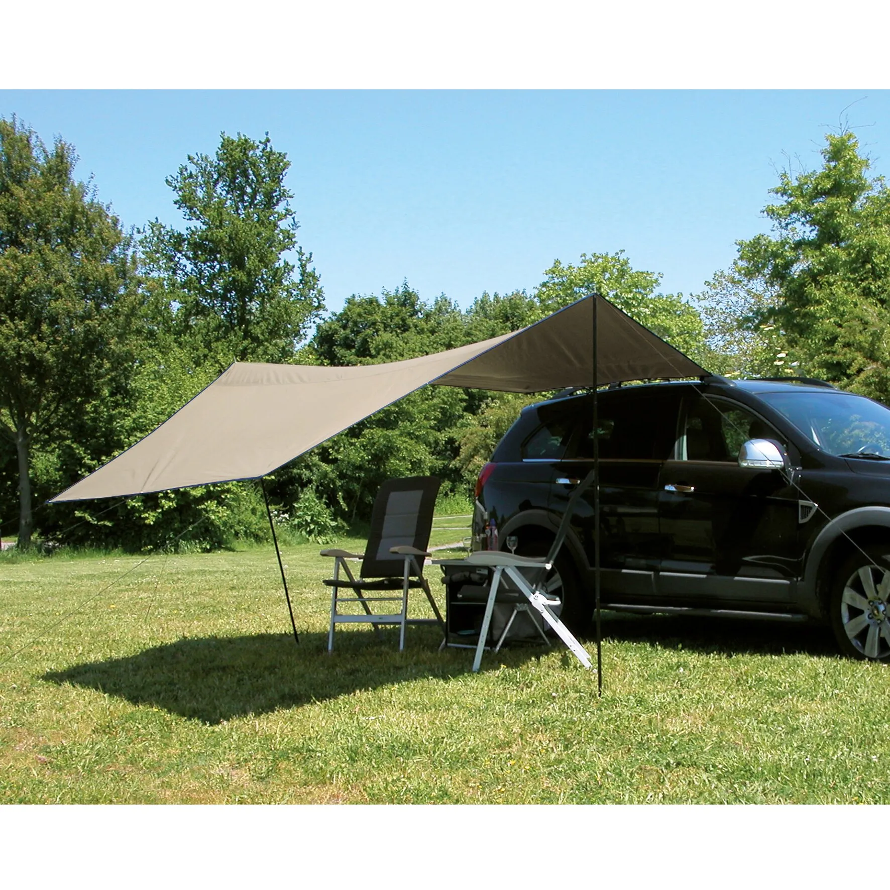 Beiges Sonnensegel Tarp Carside am schwarzen Auto befestigt, mit zwei Campingstühlen auf einer Wiese unter Bäumen
