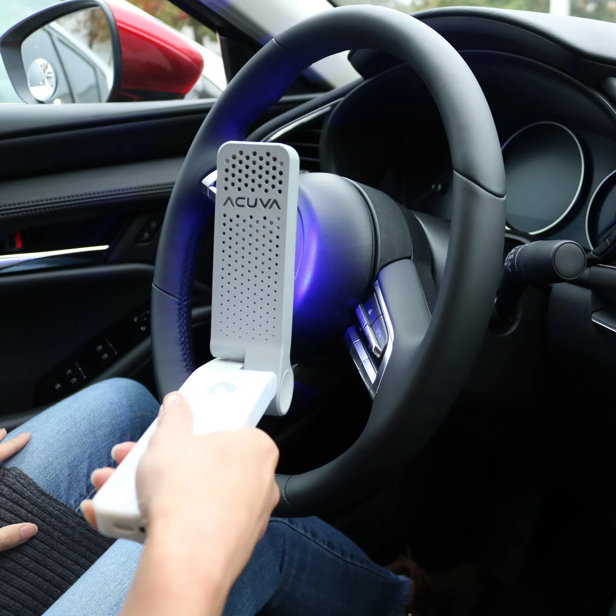Acuva Solarix Oberflächen-Desinfektionsgerät wird im Auto am Lenkrad eingesetzt und leuchtet blaues UV-Licht aus
