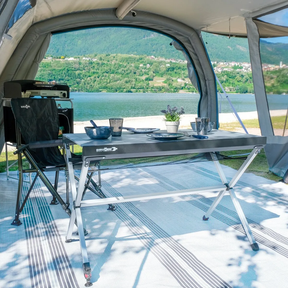 Rolltisch Titanium Axia von Brunner mit grauer Tischplatte und Aluminiumgestell im Vorzelt am See gedeckt genutzt