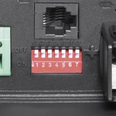 Detailaufnahme des DCC-Ladeboosters PerfectPower 24 V, 20 A mit RJ45-Anschluss und sieben roten DIP-Schaltern
