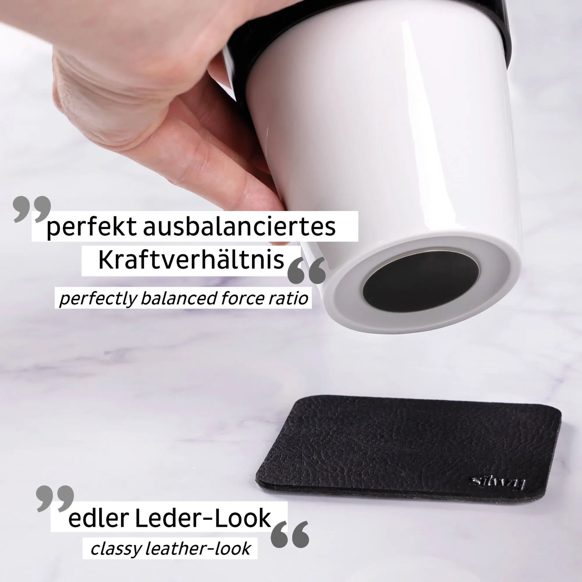 Weiße Porzellan-Kaffeebecher TO-GO-CUP mit schwarzem Deckel wird von einer Hand gehalten; daneben liegt ein schwarzes Etui in Lederoptik