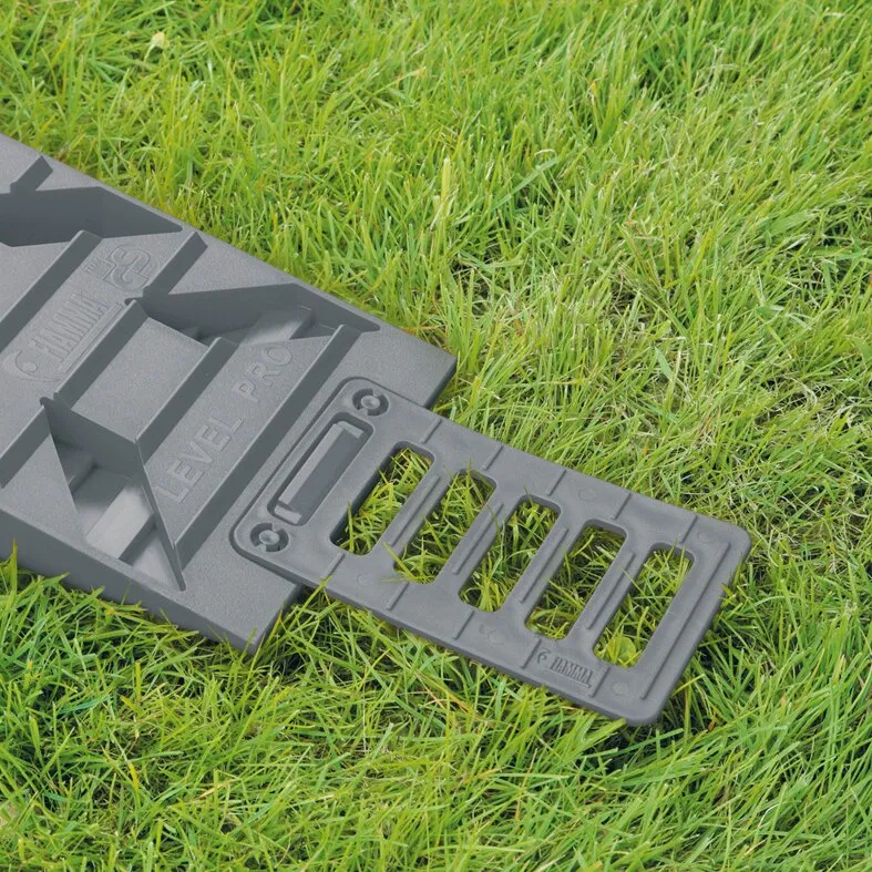 Schwarzer Auffahrkeil Level Pro mit Auffahrrampe und rutschhemmenden Stufen auf einer grünen Rasenfläche
