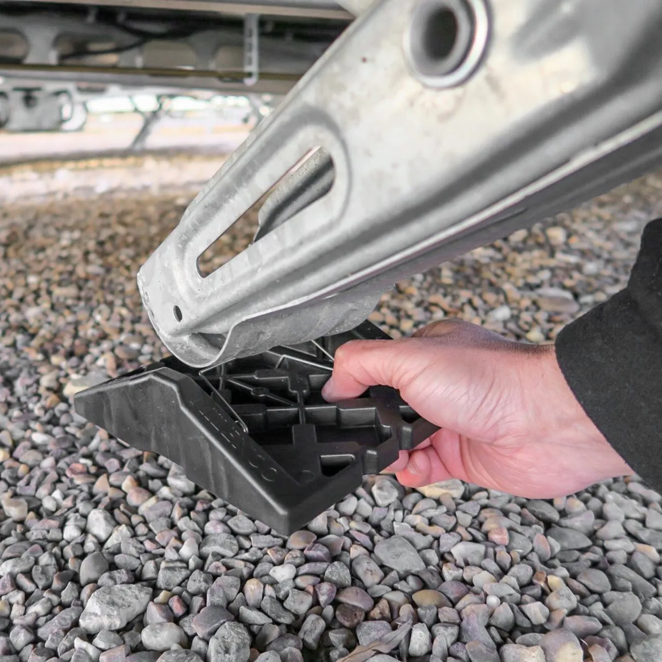 Schwarze Stützplatte Corner Feet wird unter einem Metallstützfuß auf einem Kiesuntergrund positioniert