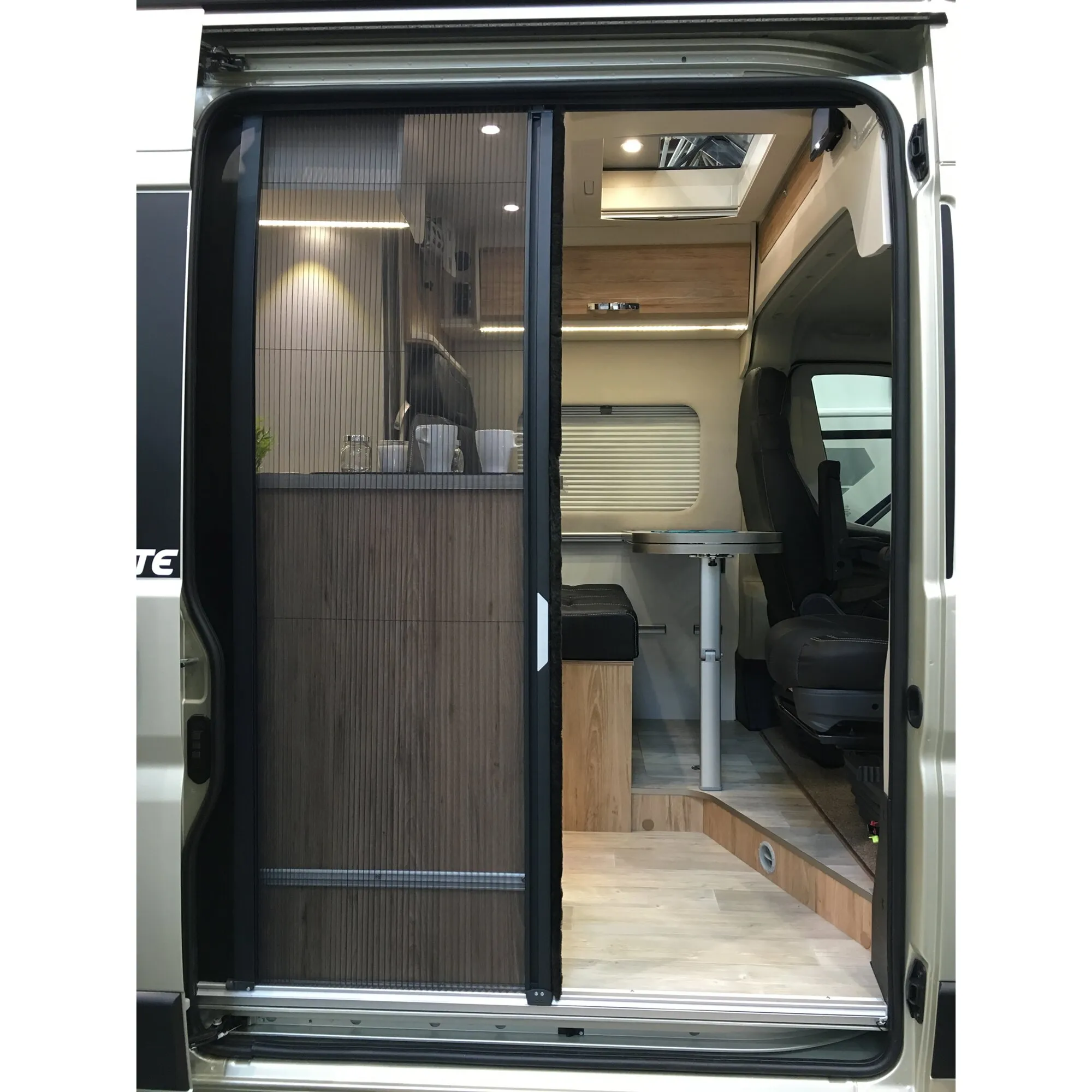 Plissee-Fliegenschutztür in schwarzem Rahmen an der geöffneten Schiebetür eines ausgebauten VW Crafter oder MAN TGE