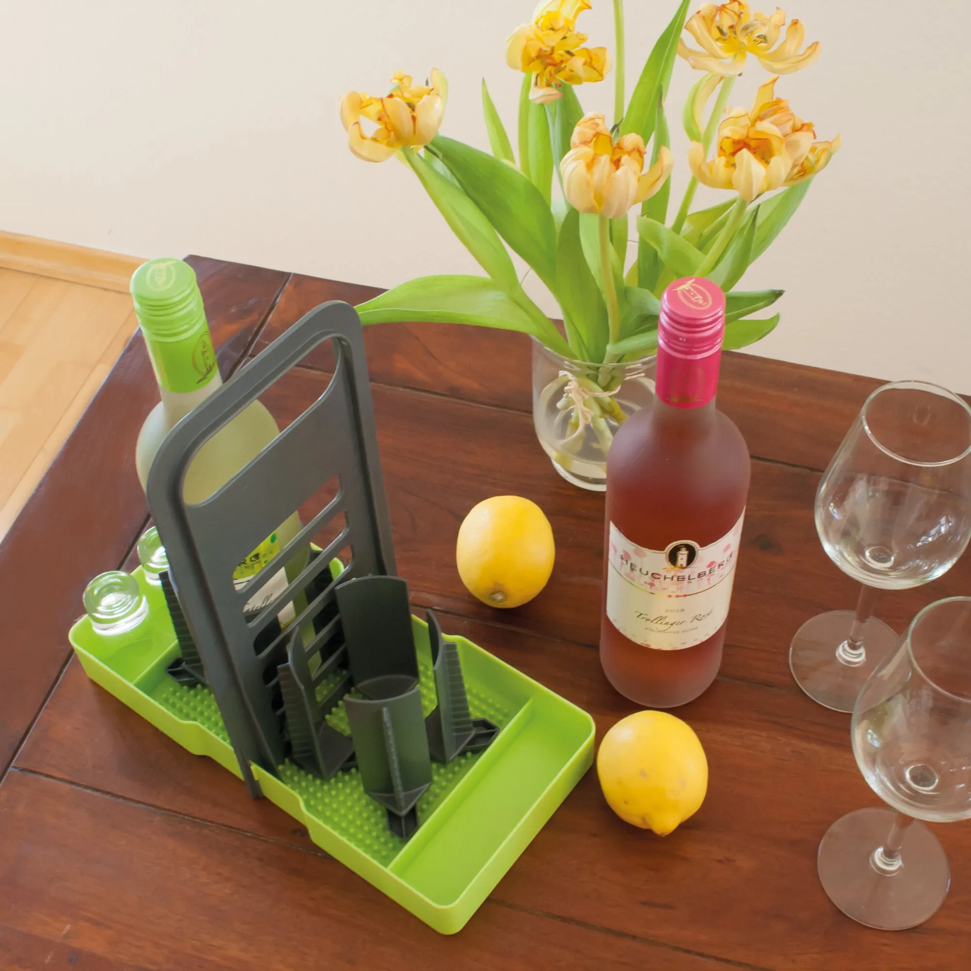 Limegrüner Flaschenhalter Multi Tray OELE mit grauen Trennstegen und Flaschen auf einem gedeckten Holztisch neben Wein und Gläsern
