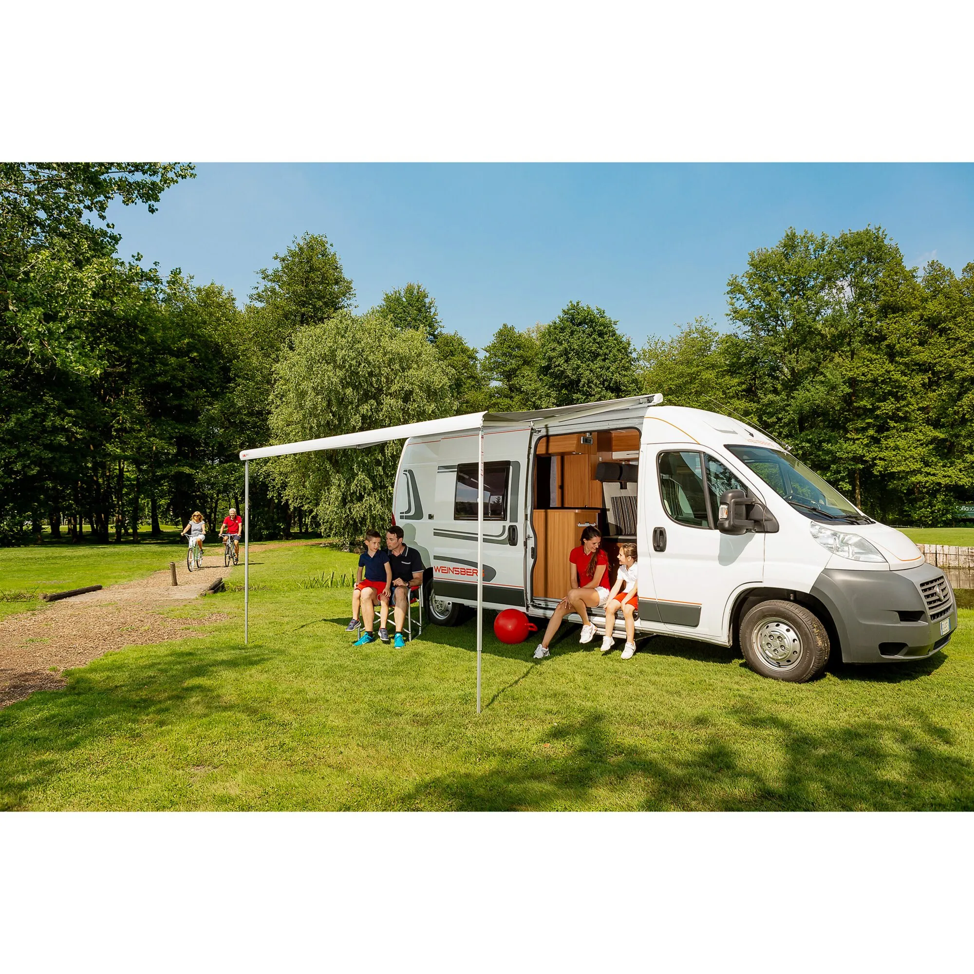 Polarweiße F80-Markise in Royal Grey, 290 cm, ausgefahren an einem weißen Wohnmobil im Campingpark mit sitzender Familie