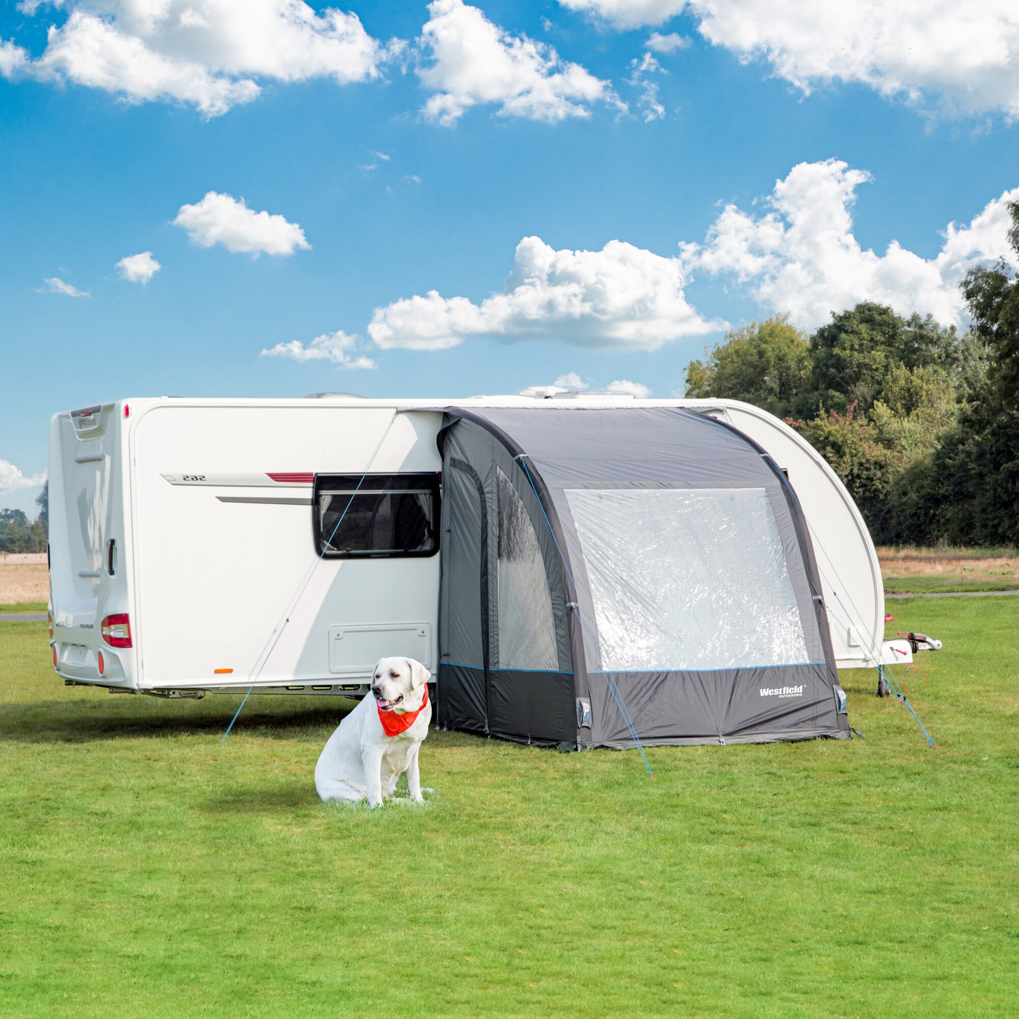 Teilzelt Lynx 200 cm an einem weißen Wohnmobil; Westfield Outdoors Vorzelt, grüne Wiese, Himmel, weißer Hund mit rotem Halstuch davor