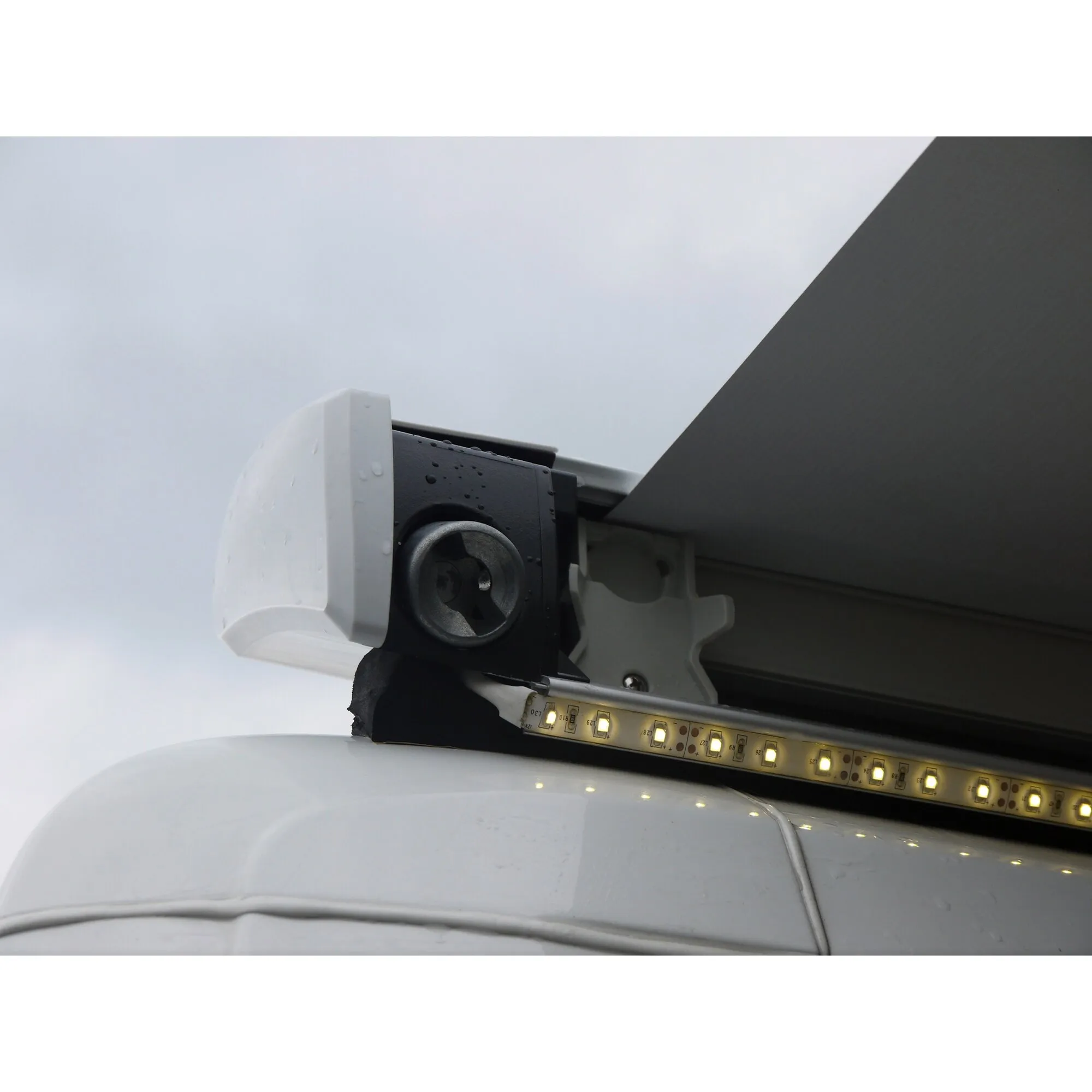 Detailaufnahme der LED-Strip-Fixierung für eine Omnistor-Markise 6200/6300/9200 mit leuchtendem LED-Band am weißen Fahrzeug