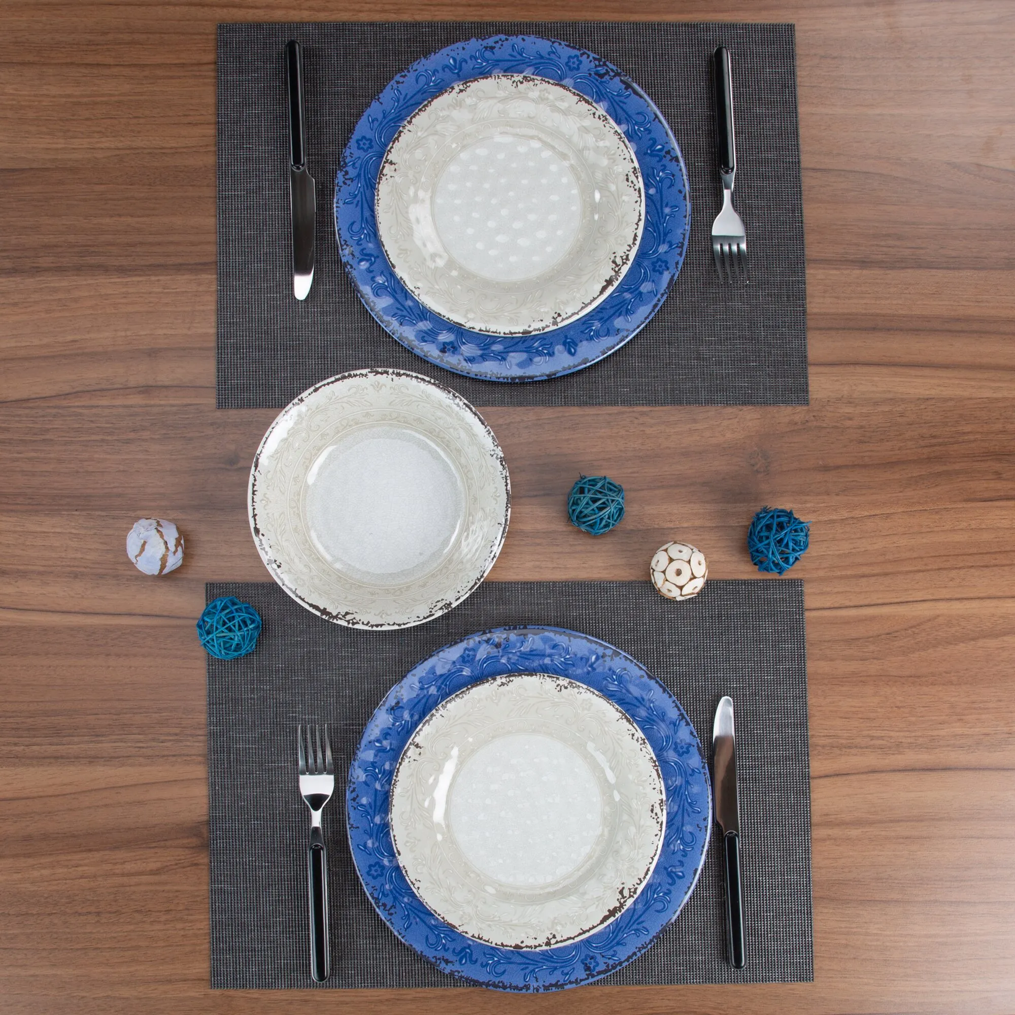 Geschirrset Stone Line mit blau verzierten Tellern auf schwarzen Platzsets, Besteck und dekorativen Holzkugeln auf einem Holztisch