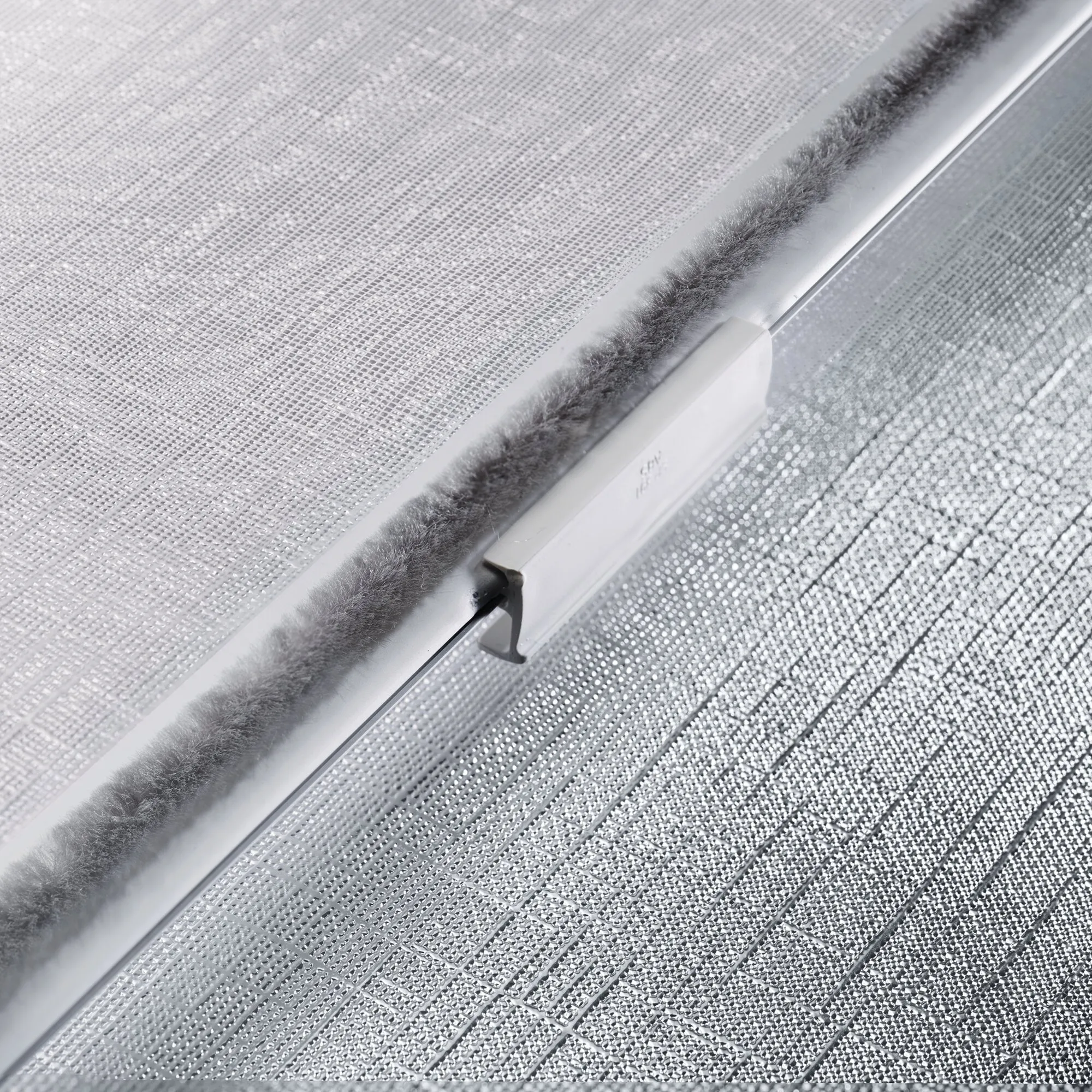 Detailaufnahme des weißen Dometic Rastrollo 3000 mit lichtdurchlässigem Rollo-Gewebe, Führungsschiene und grauer Bürstendichtung