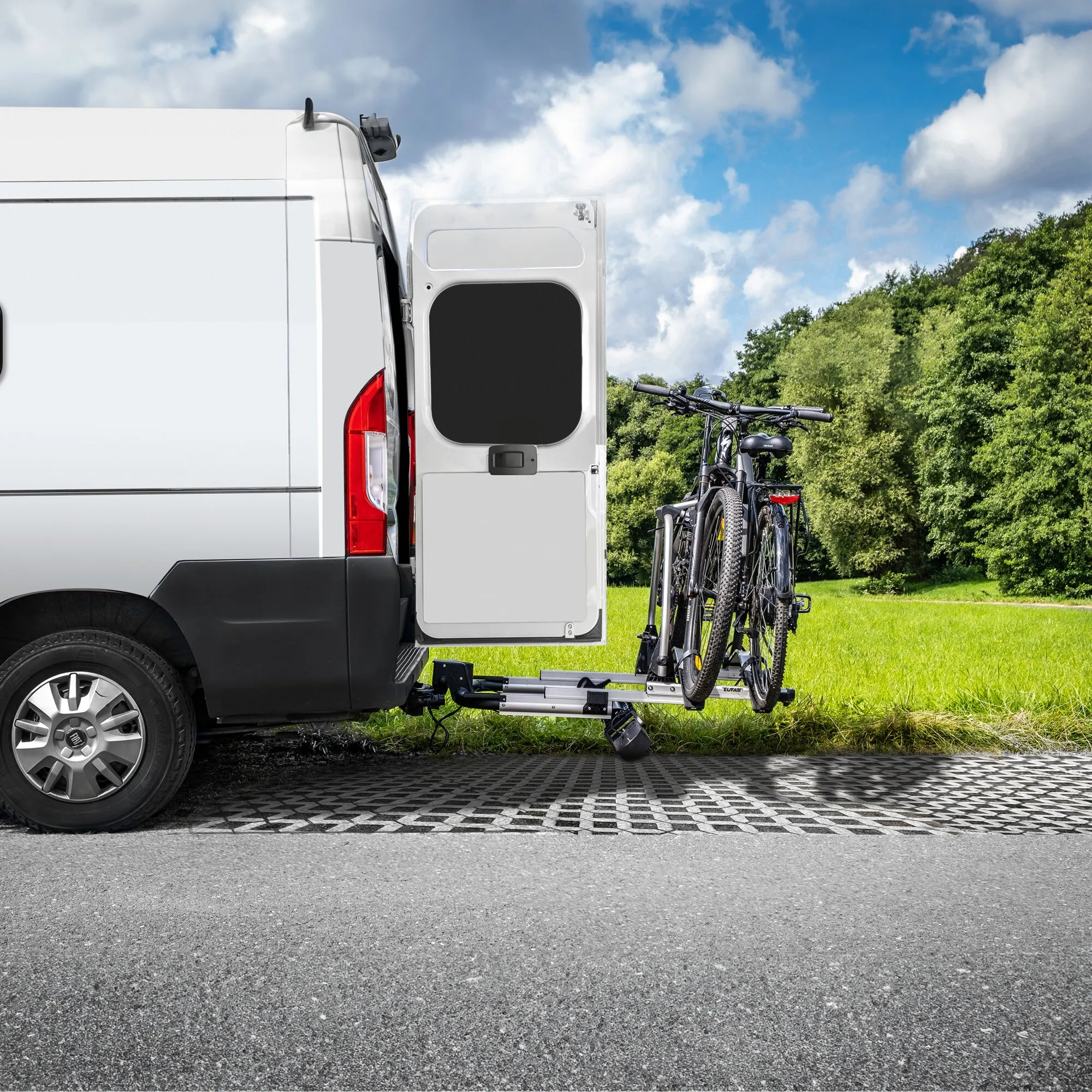 Silberner Fahrradträger SD260 an der Anhängerkupplung eines weißen Transporters mit zwei befestigten Fahrrädern