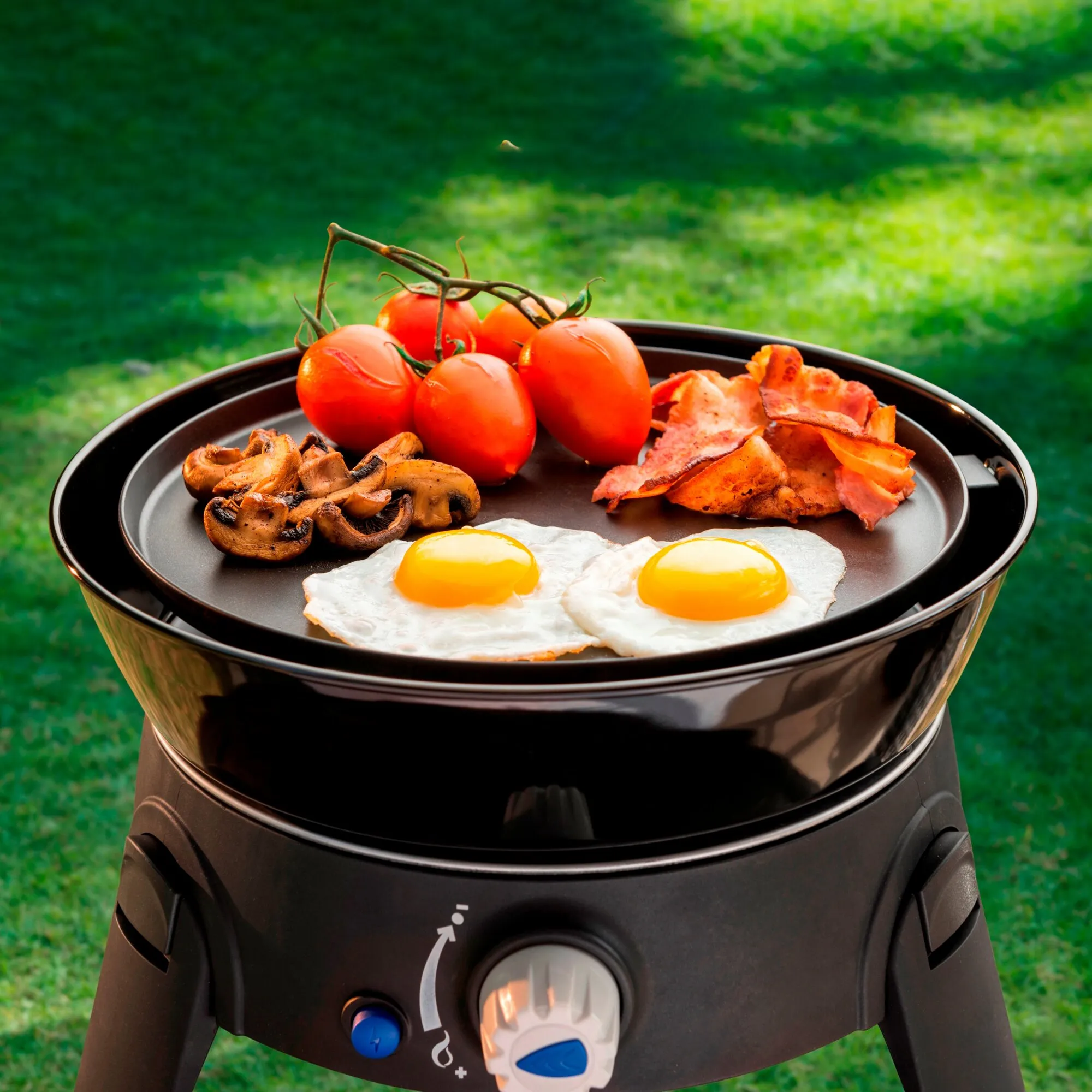 Gasgrill Safari Chef 30 in Schwarz mit Grillplatte, Spiegeleiern, Tomaten, Pilzen und gebratenem Fleisch im Garten