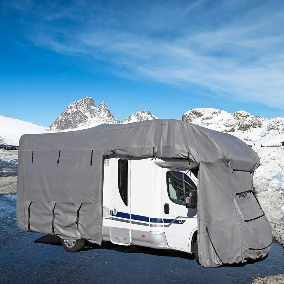 Graue Reisemobil-Schutzhülle Camper Cover 6M über einem weißen Wohnmobil in verschneiter Berglandschaft