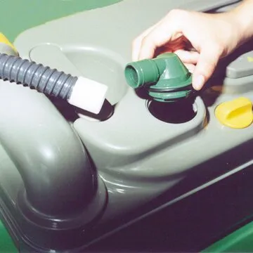 Hand verbindet einen grünen Anschluss der elektrischen WC-Entlüftung mit einer grauen Thetford-Cassettentoilette der Türvariante