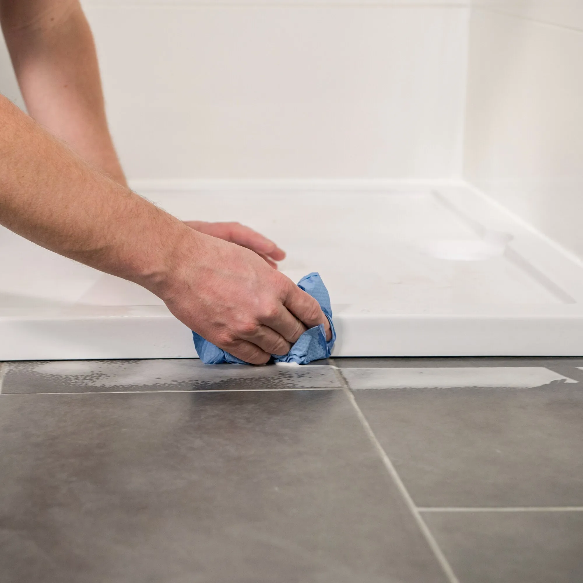 Person wischt mit blauem Tuch eine weiße Badewanne mit dem Schaumreiniger MULTICLEAN sauber