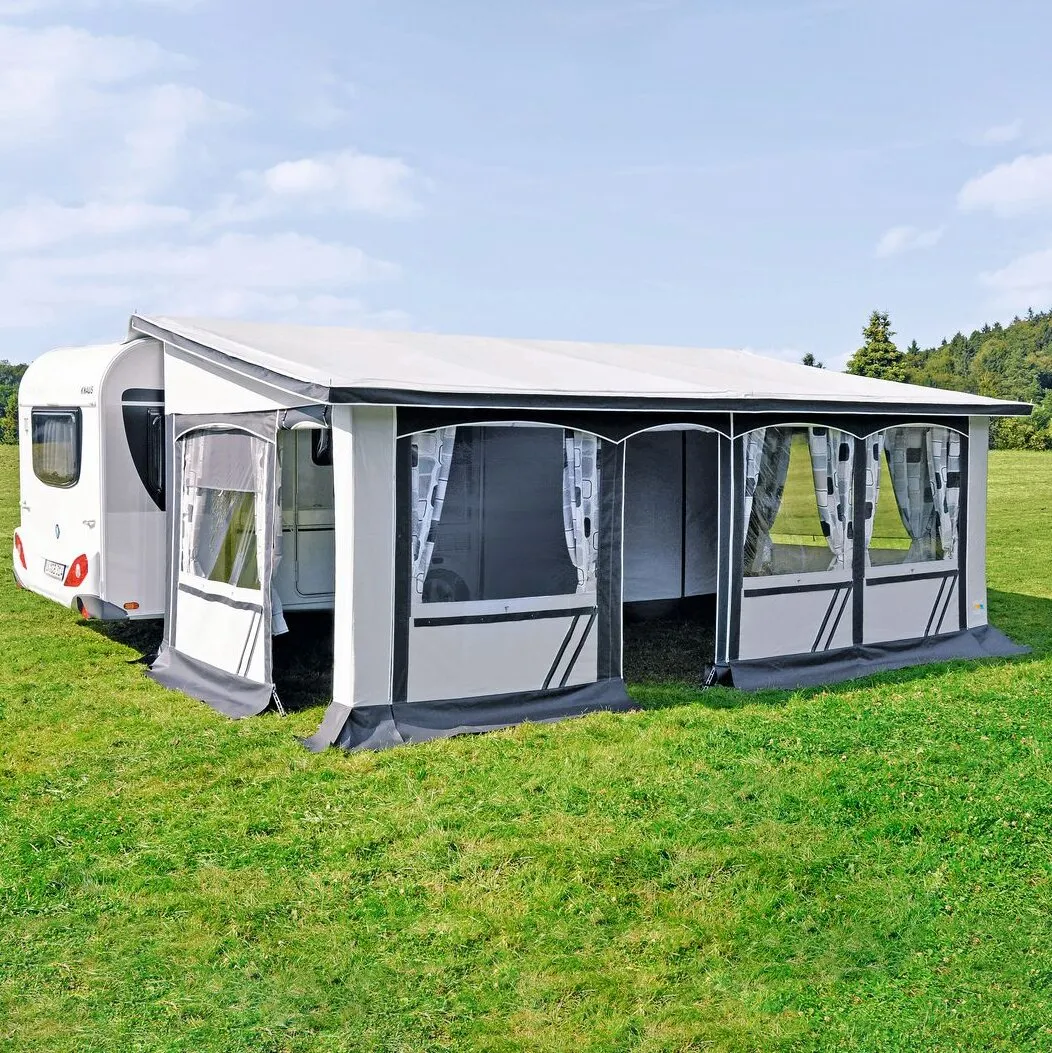 Dauervorzelt Allgäu 300 in Grau und Weiß, 650 cm, an einem weißen Wohnwagen auf einer Wiese aufgebaut