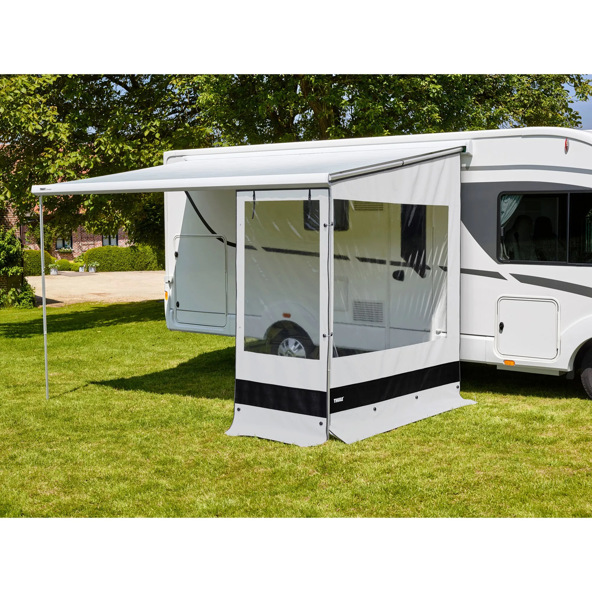 Thule Rain Blocker G2 Front in Weiß mit transparenten Fenstern am ausgefahrenen Wohnmobilvorzelt auf einer Rasenfläche