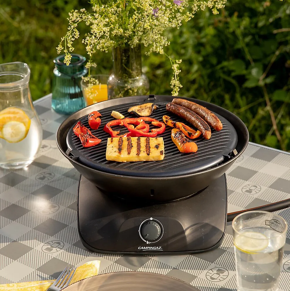 Schwarzer runder Campingaz Tischgrill 360 Grill CV mit Grillrost, Würstchen, Gemüse und Grillkäse im Garteneriwa
