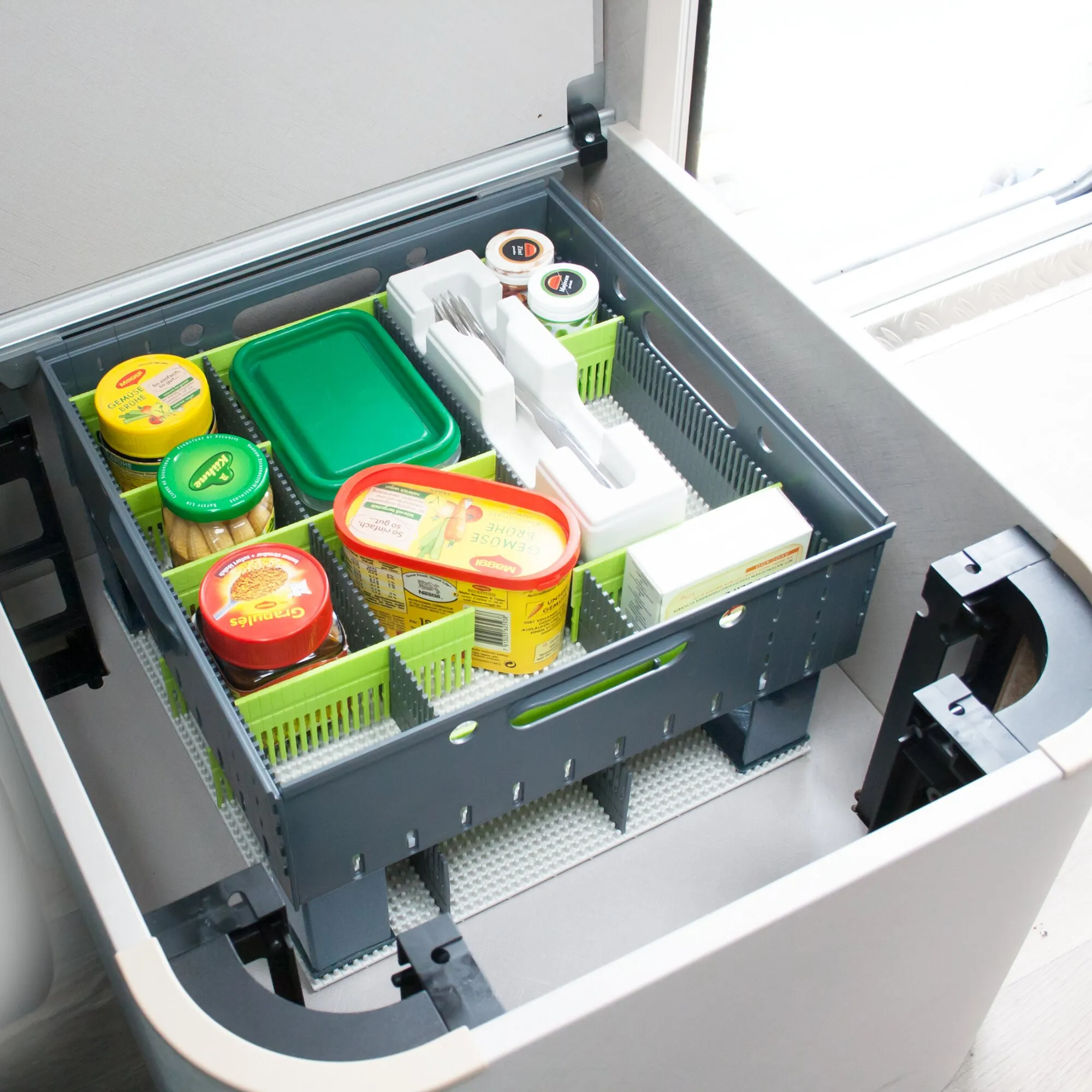 Offene dunkelgraue Staubox mit grünen Fächern zur Aufbewahrung von Lebensmitteln und Besteck in einem Fahrzeugข้อความเต็ม
