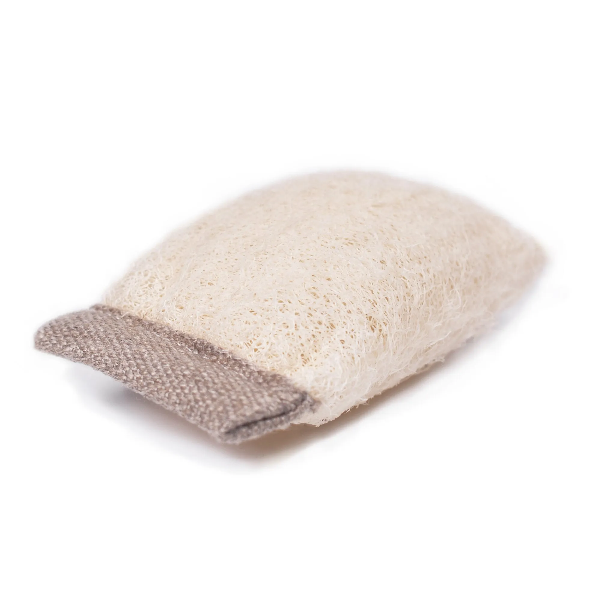Cremefarbener Luffa-Schwamm mit braunem Rand als Ablage für feste Reiniger, freigestellt auf weißem Hintergrund