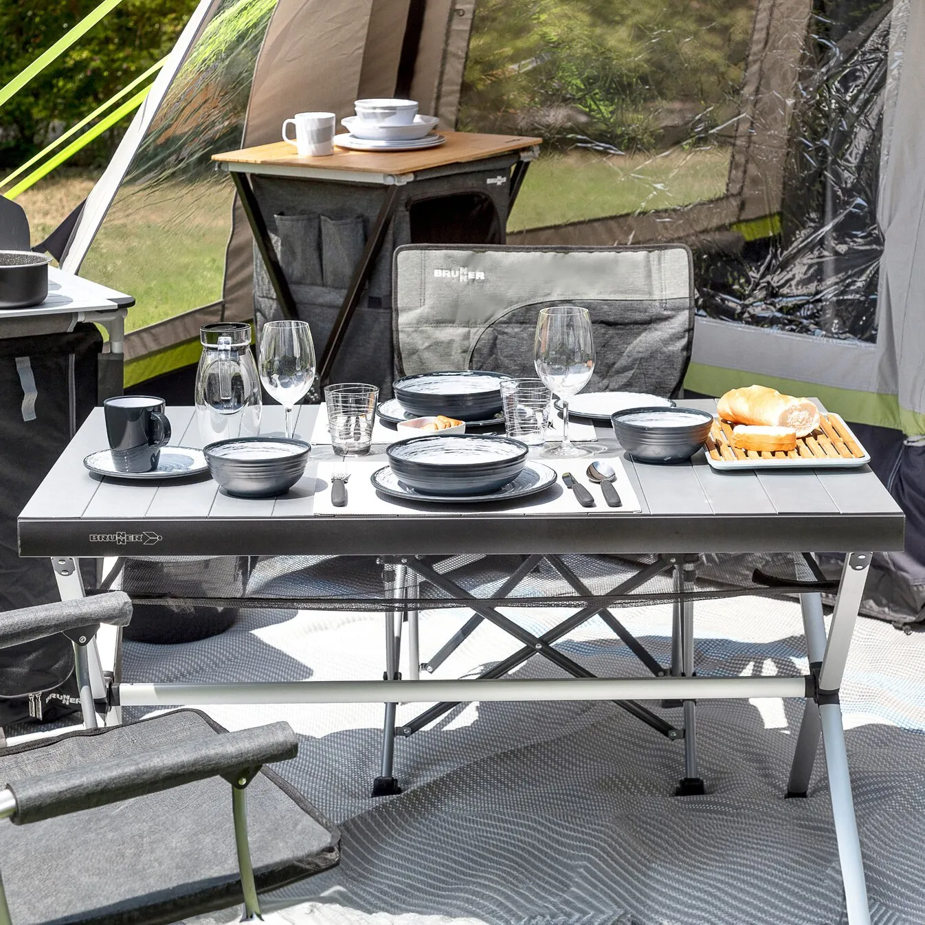 Rolltisch Accelerate 120 cm mit grauer Tischplatte im Campingzelt, gedeckt mit Geschirr und Getränken geschniegelt