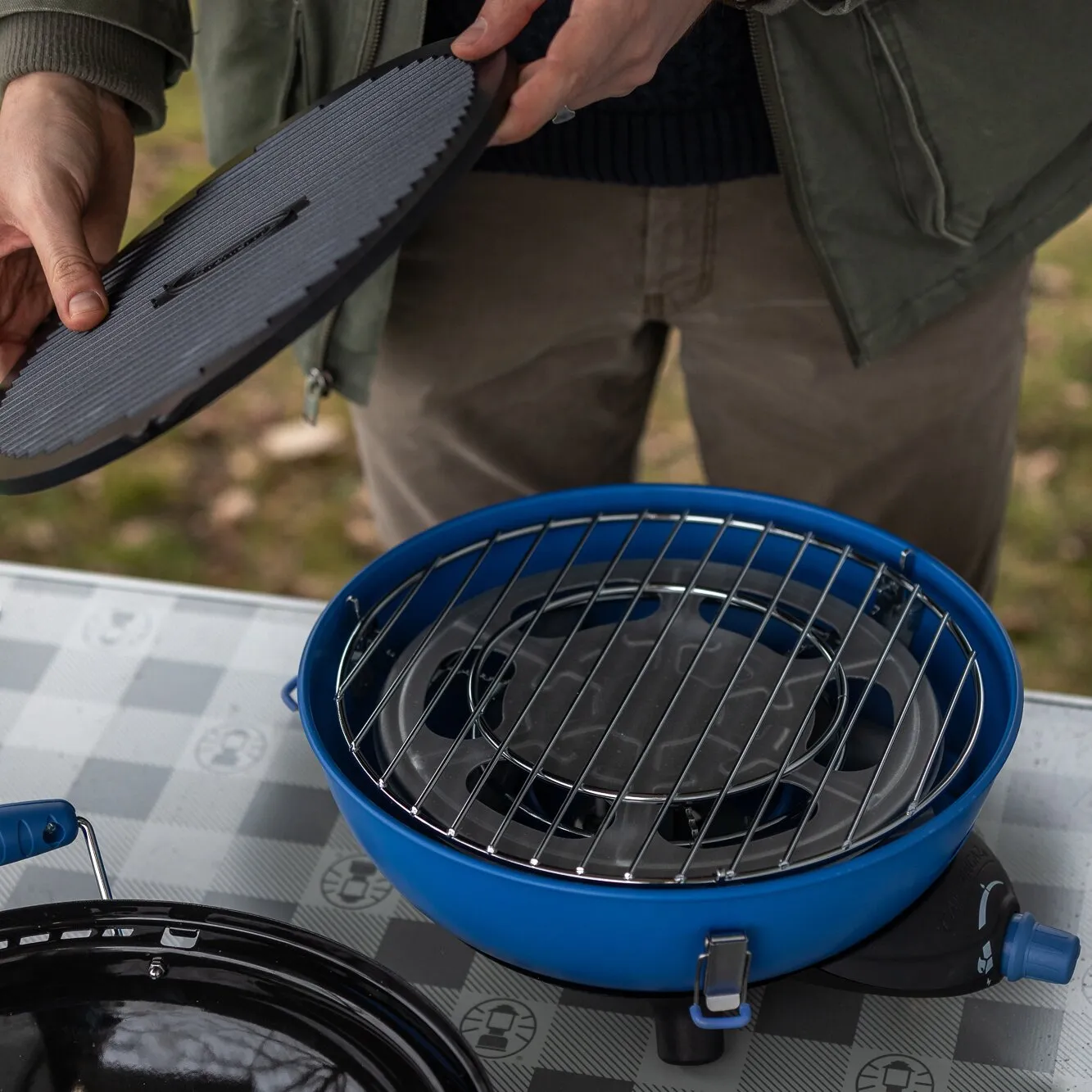 Blauer runder Party Grill 400 Caravan Connect mit Grillrost, geöffnetem Deckel und sichtbarem Gasanschluss in der Anwendung unerquicklich