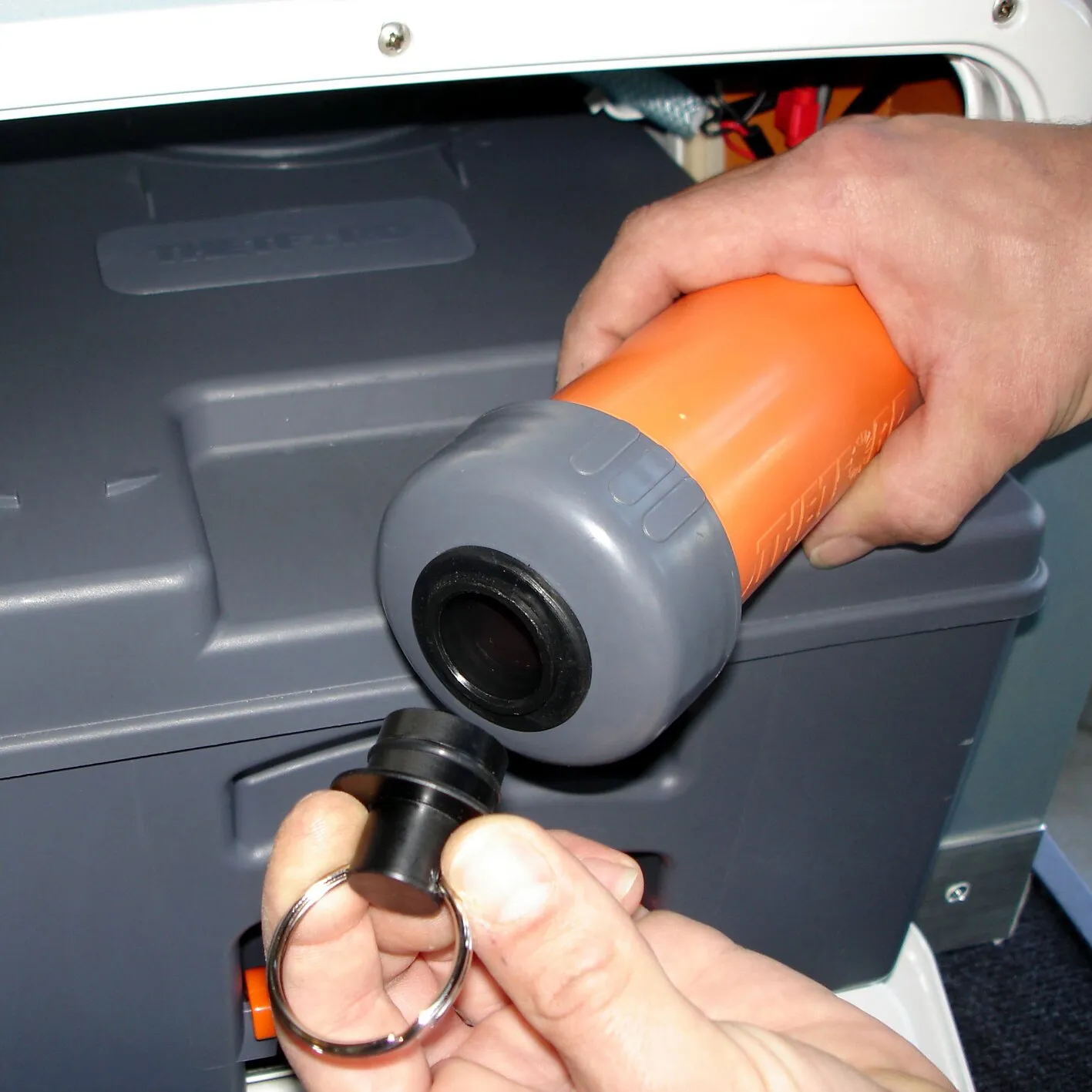 Montage einer orange-grauen elektrischen WC-Entlüftung am C250 oder C260 mit schwarzem Anschlussstutzen in der Handwerkerhand