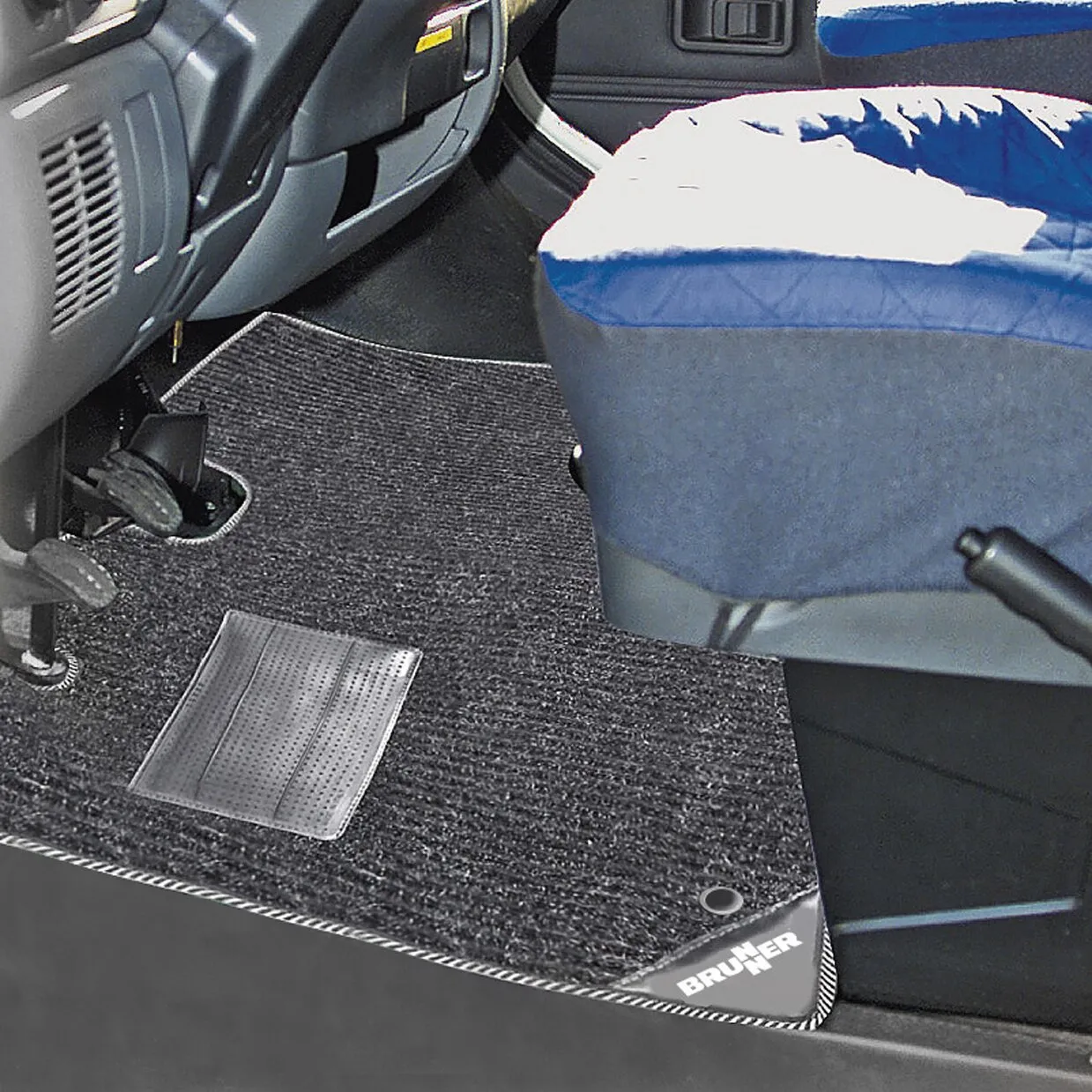 Schwarzer Teppich Deluxe mit Metallpedalbereich im Fußraum eines Ford Transit, passend an Sitzkonsole und Fahrzeugboden verlegt