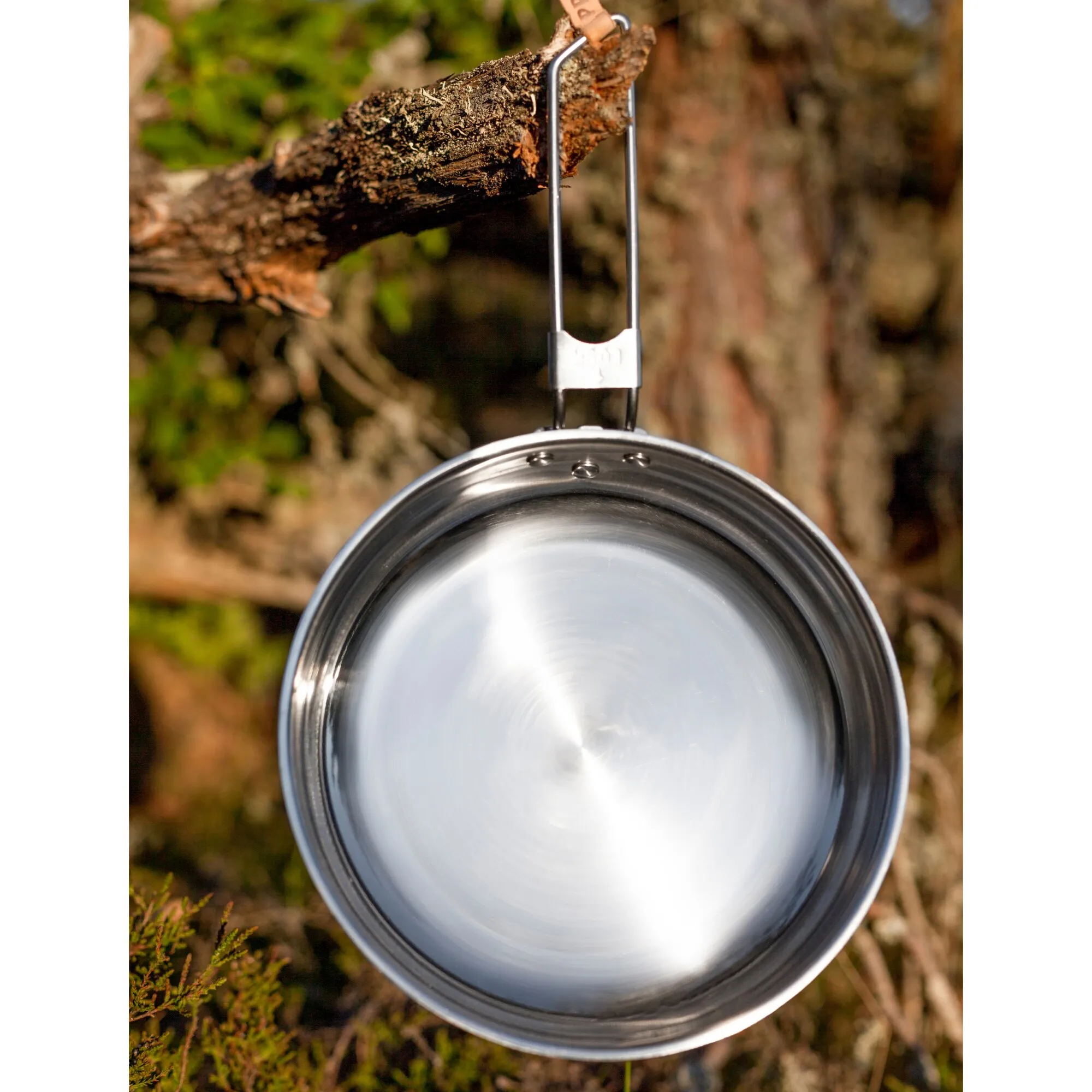 Kochtopf-Set Campfire L aus glänzendem Edelstahl, an einem Ast im Wald aufgehängt, mit sichtbarem Klappgriff