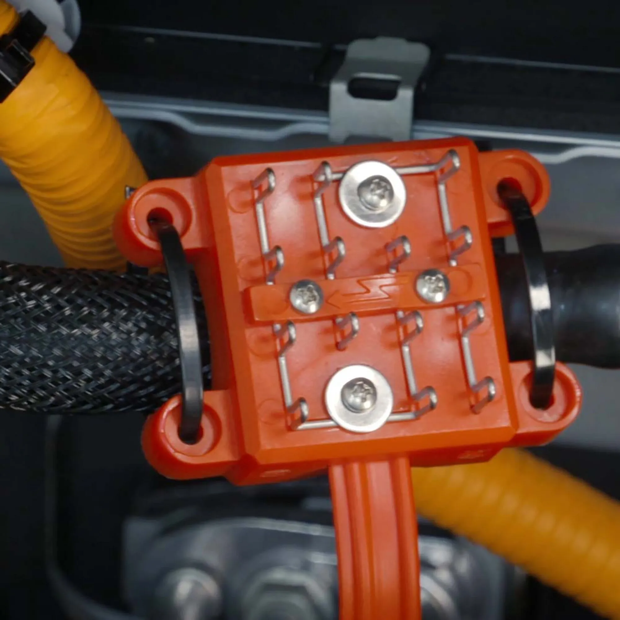 Detailaufnahme des roten Marderabwehrgeräts M9300 mit Metallkontakten und schwarzen Befestigungsbändern im Motorraum