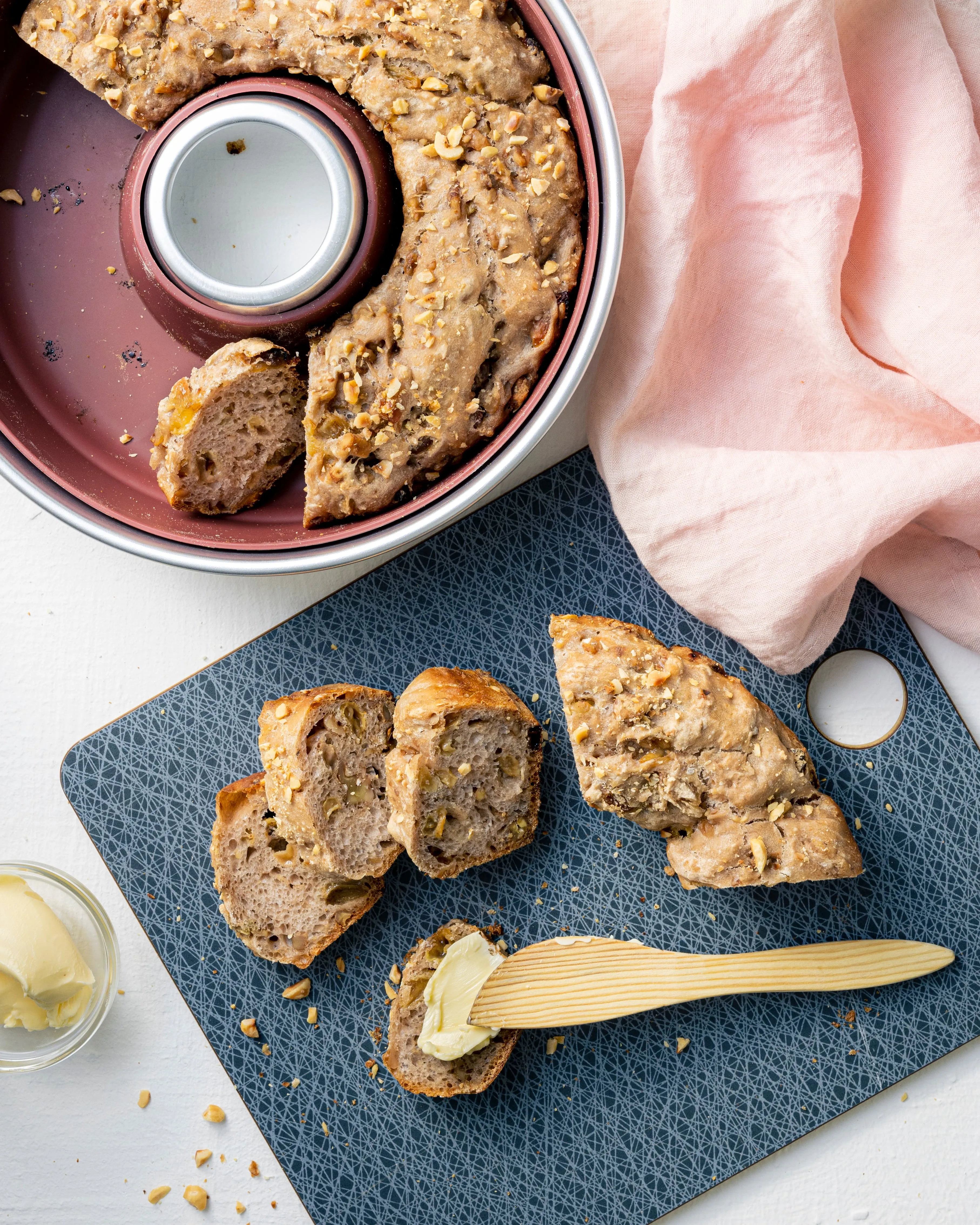 Bordeauxrote Silikonform mit Metallring, in der ein mit Nüssen bestreutes Brot gebacken wird