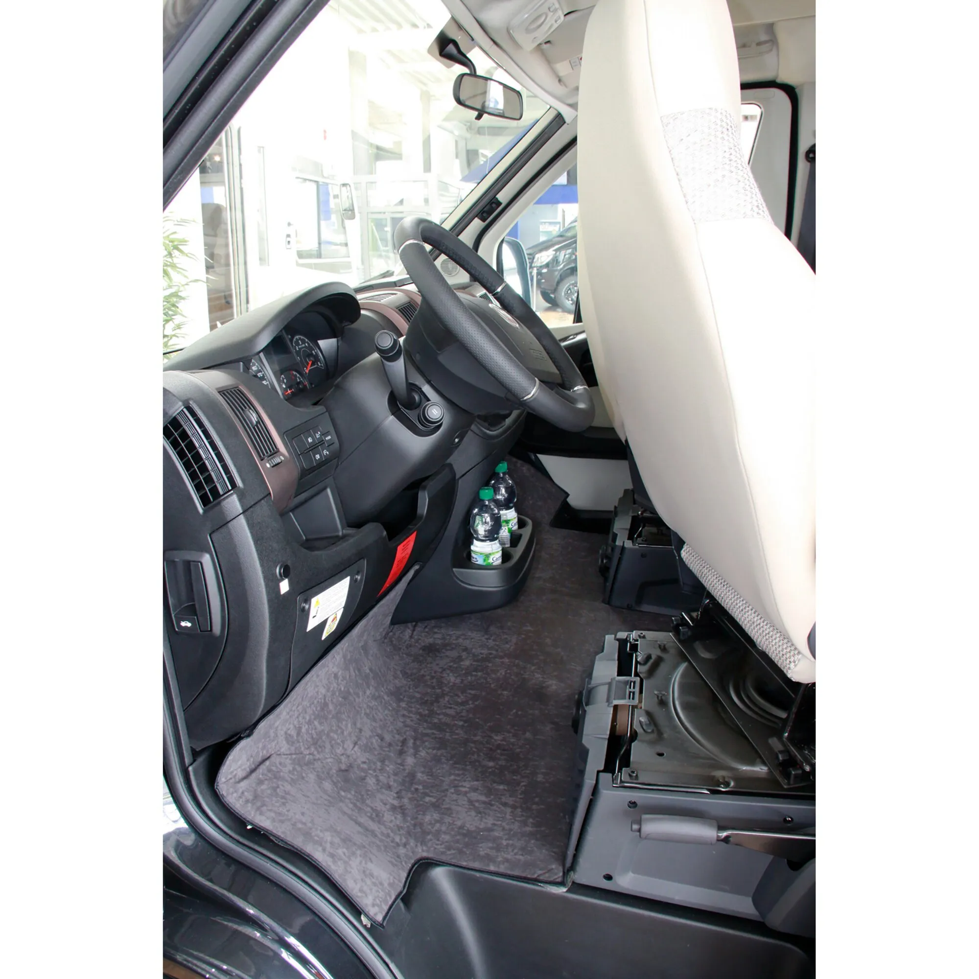 Graue Fußraumisolierung im Fahrerhaus eines VW Crafter Gen. 2, um Fahrersitz, Armaturenbrett und Mittelkonsole verlegt