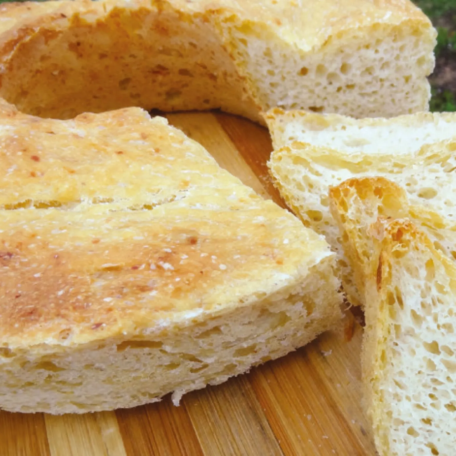 Aufgeschnittene goldbraune Brote mit lockerer, großporiger Krume auf einem Holzbrett aus dem Backbuch für den Omnia Backofen