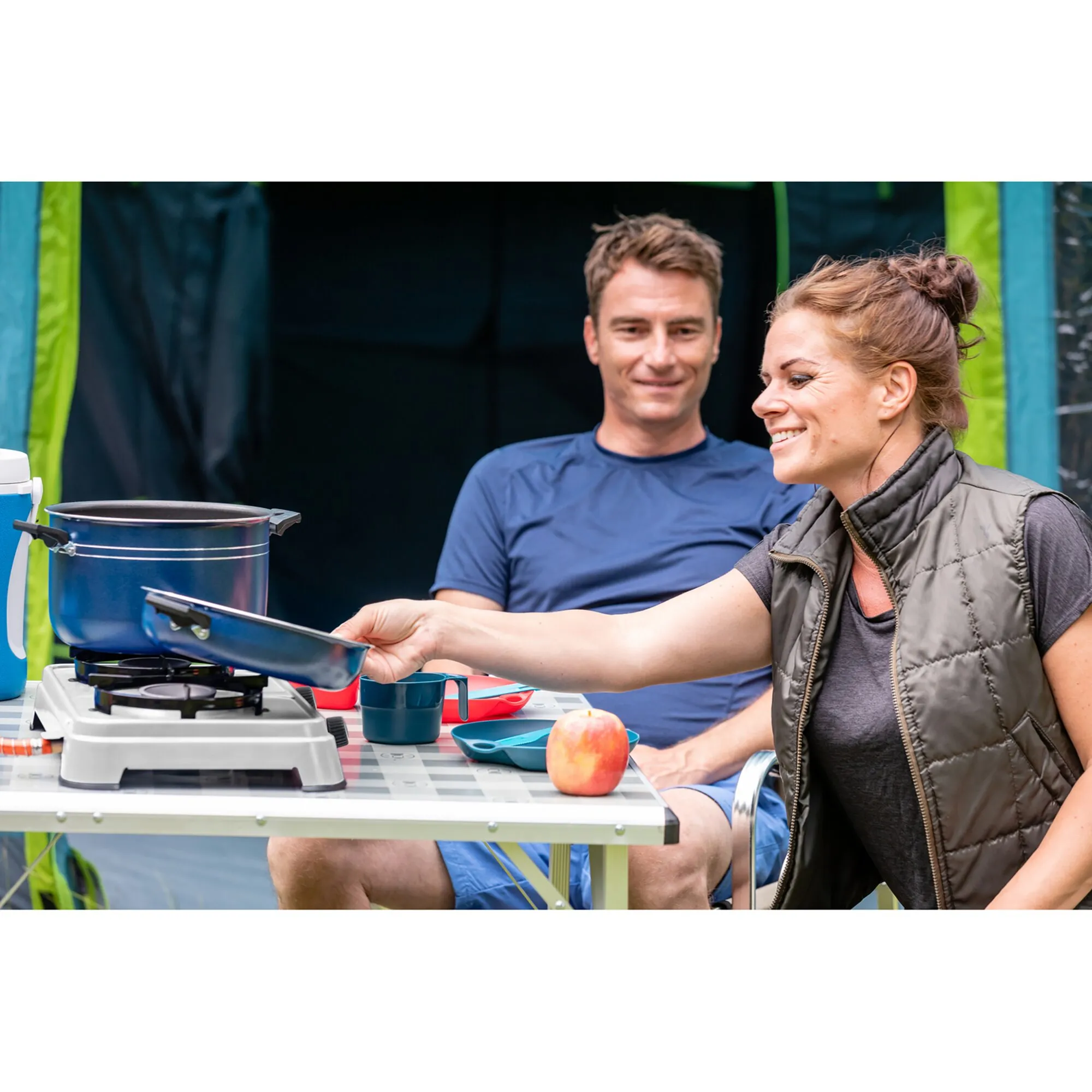 Campingkocher Camping Cook CV mit blauem Topf und Pfanne beim Kochen auf einem Campingtisch vor einem Zelt unerquicklich