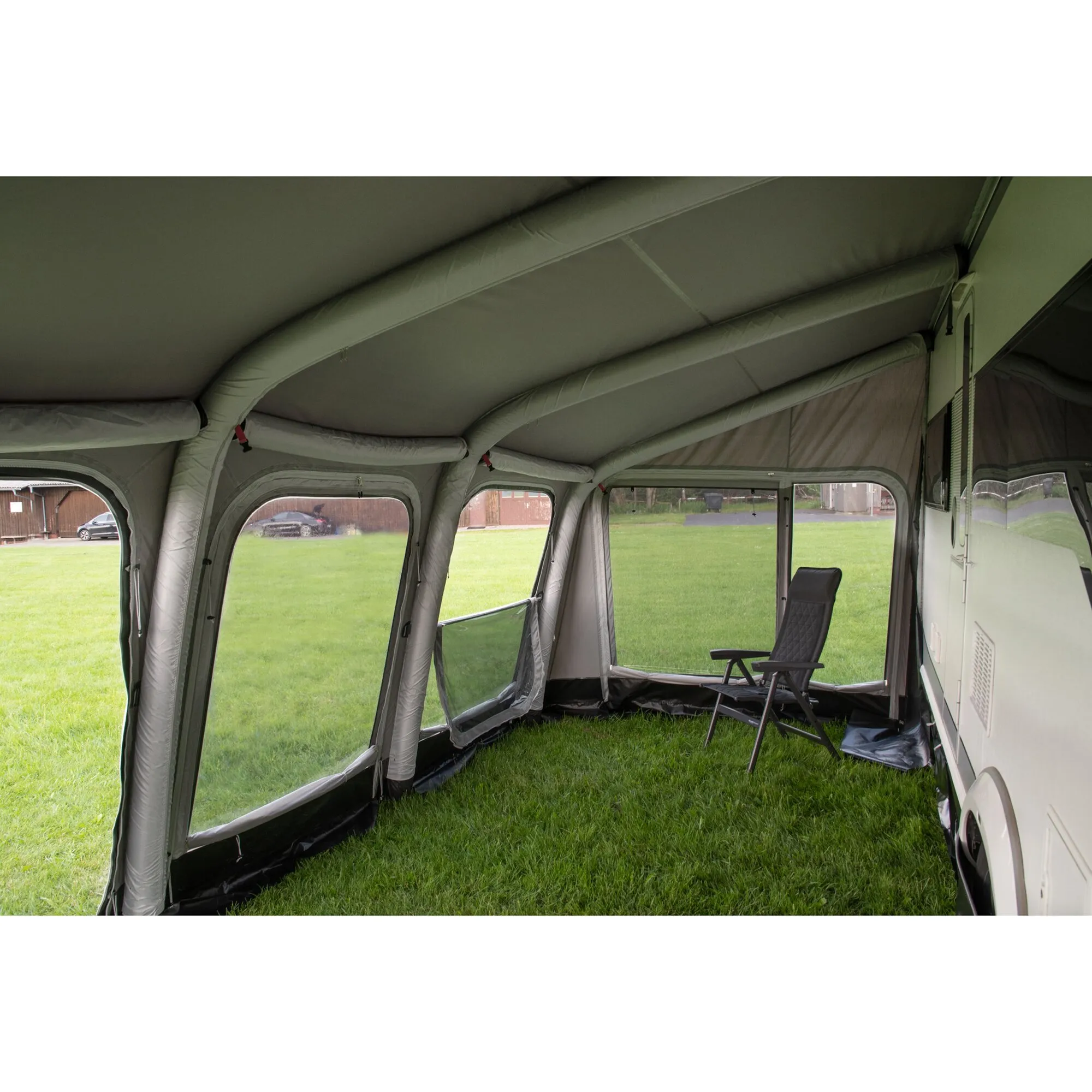 Innenansicht des grauen Reisevorzelts Ceres mit aufblasbaren Rahmen, großen Fenstern und Campingstuhl am Wohnwagen gras.