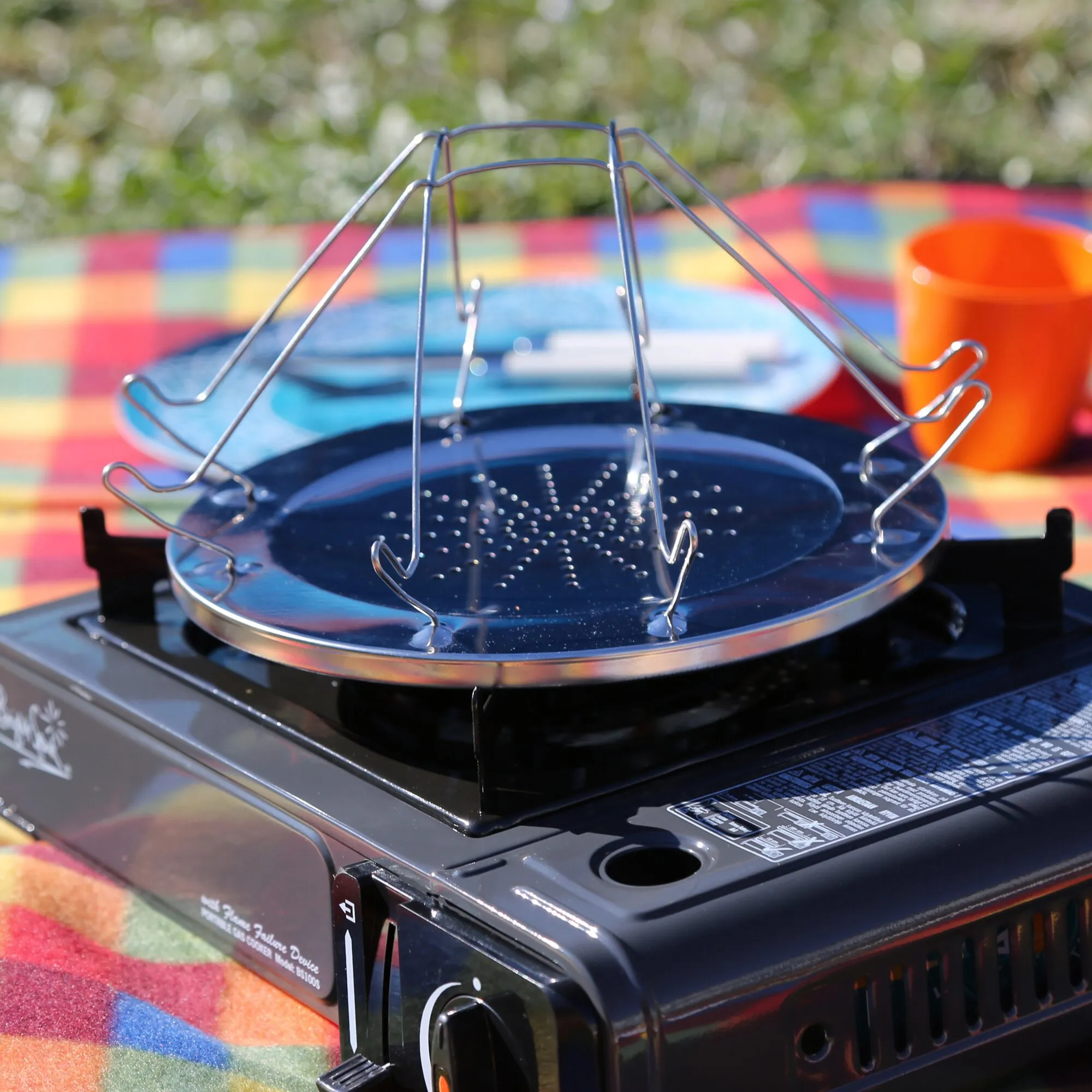 Edelstahl-Campingtoaster mit klappbarem Drahtgestell auf einem tragbaren Gaskocher im Freien