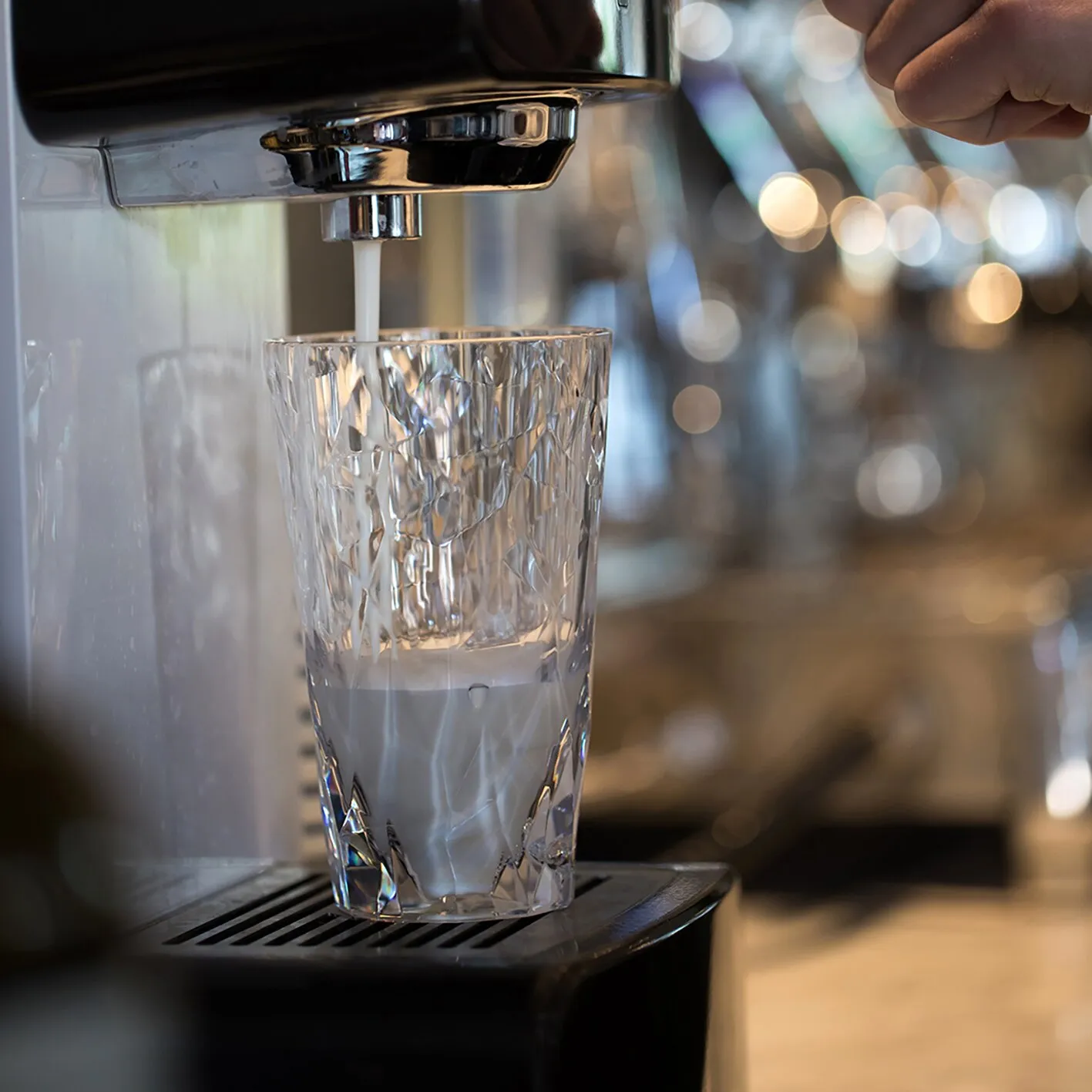 Klares Trinkglas Superglas CLUB mit facettiertem Muster, während es an einer Zapfanlage mit Wasser gefüllt wird