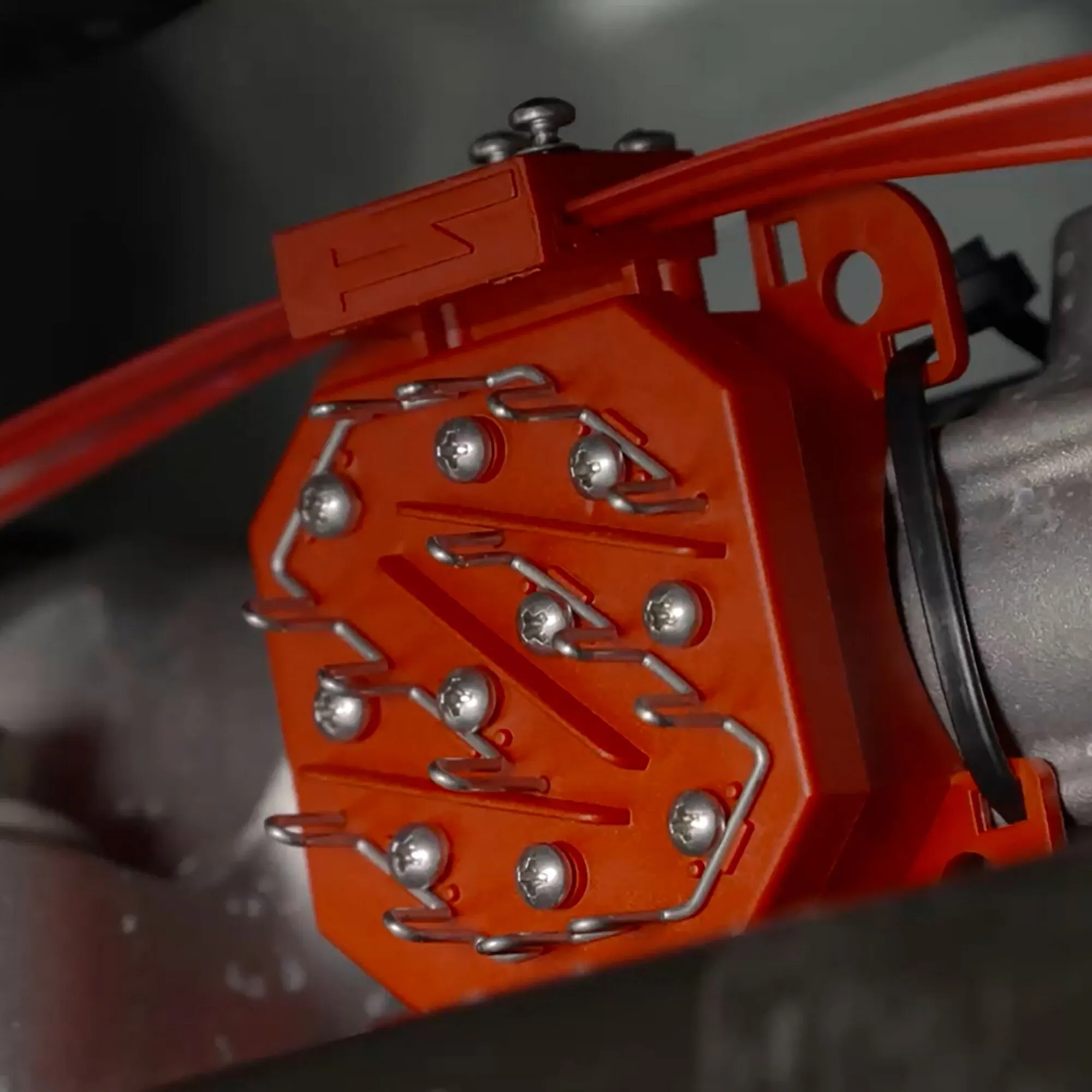 Detailaufnahme des orangefarbenen Marderabwehrgeräts M9900 mit Hochspannungskontaktplatten und roten Anschlusskabeln im Motorraum