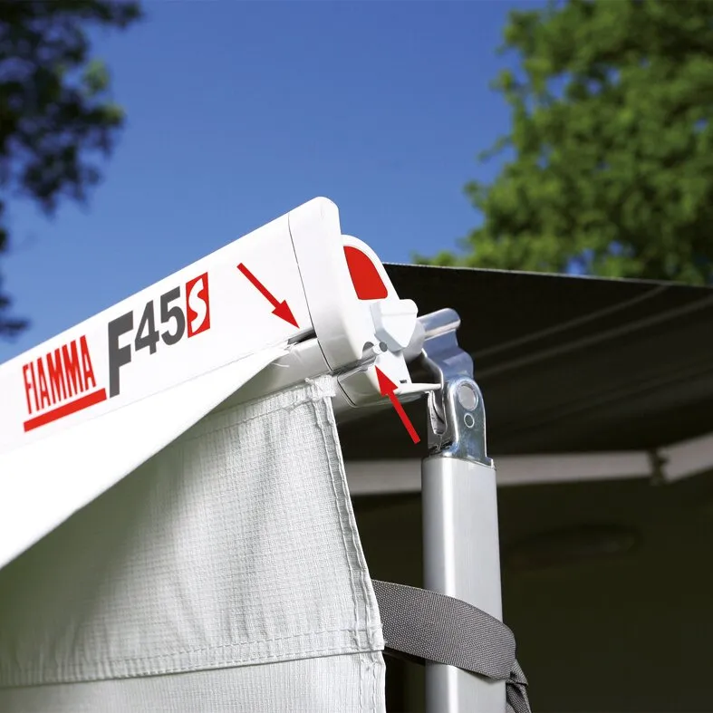 Detailaufnahme einer polarweißen Fiamma-Markise F45 mit ausgefahrenem dunkelblauem Tuch, Gelenkarm und Spannband vor blauem Himmel