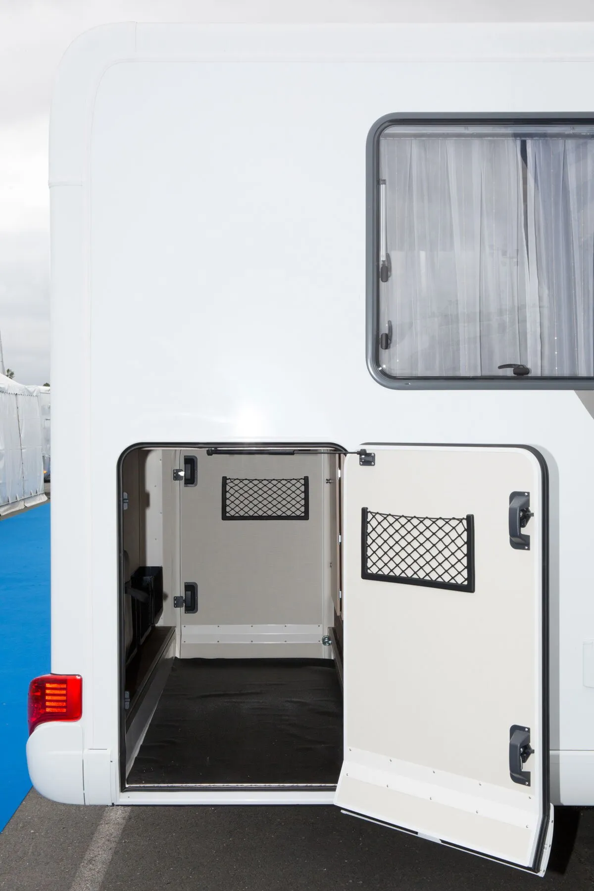 Geöffnete Seitenklappe eines weißen Wohnmobils mit schwarzen Utensiliennetzen Netray Medium an Tür und Innenwand