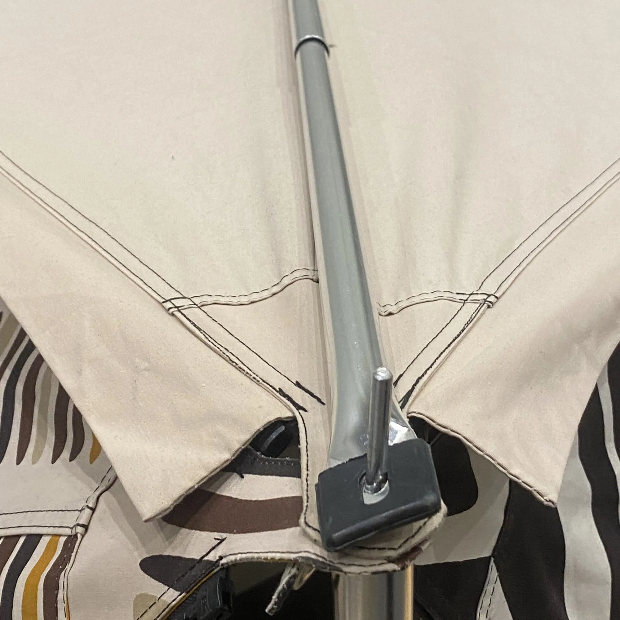 Alu-First-Spannstab aus Aluminium in einer schwarzen Halterung zwischen beigefarbenen Stoffbahnen, Detailaufnahme