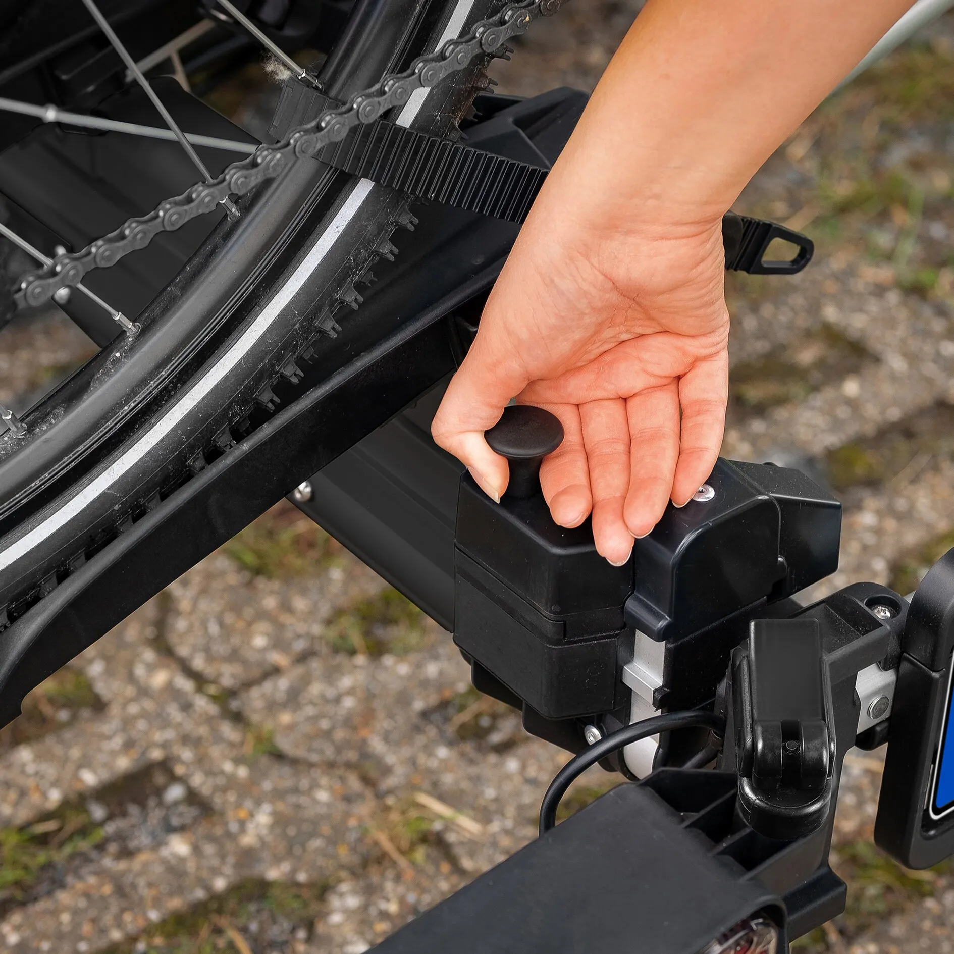 Detailaufnahme des schwarzen Fahrradträgers SD260 mit befestigtem Fahrradreifen und Hand am Spannhebel des Anhängerkupplungsträgers