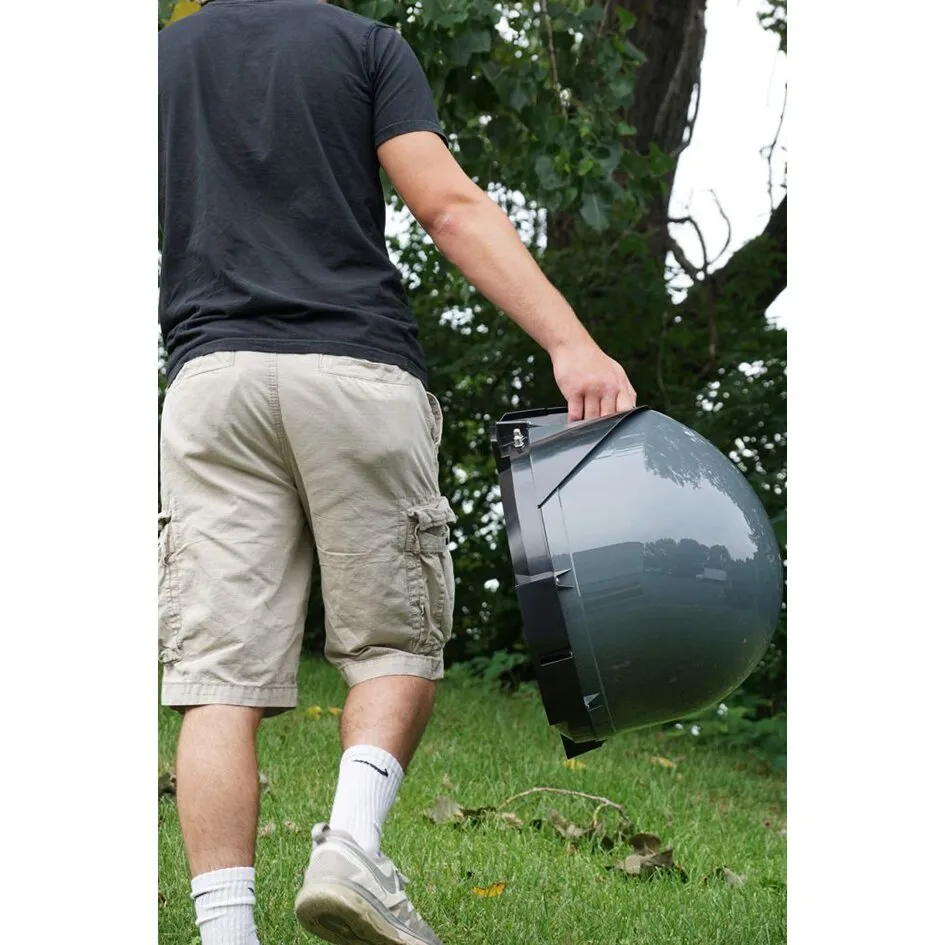 Mann trägt die graue, kugelförmige VuQube Auto II Satellitenantenne an einem Griff durch einen Garten