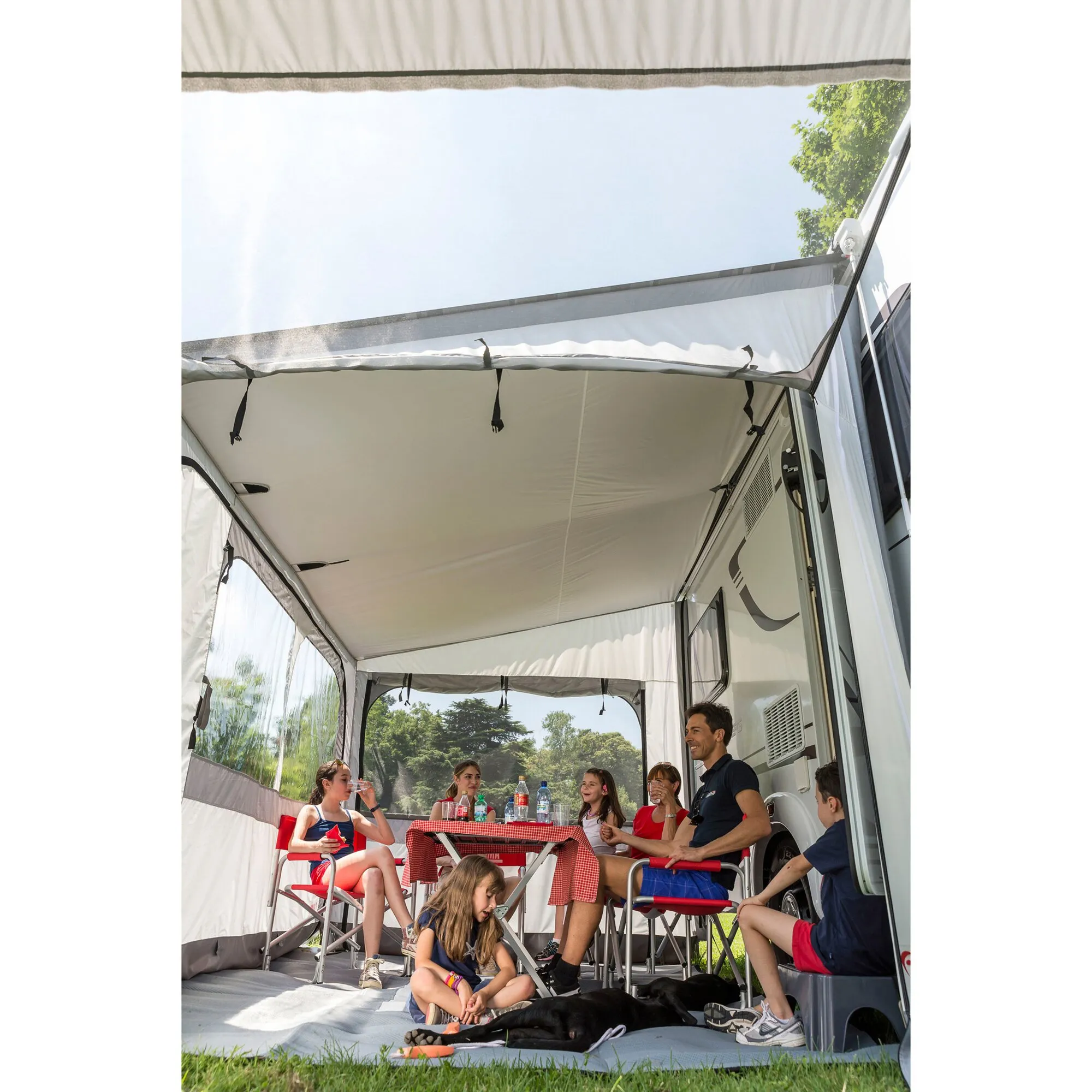 Innenansicht des weißen Markisenzeltes Privacy Ultra Light, 450 cm, mit Familie, Tisch, Stühlen und Hund am Wohnmobil