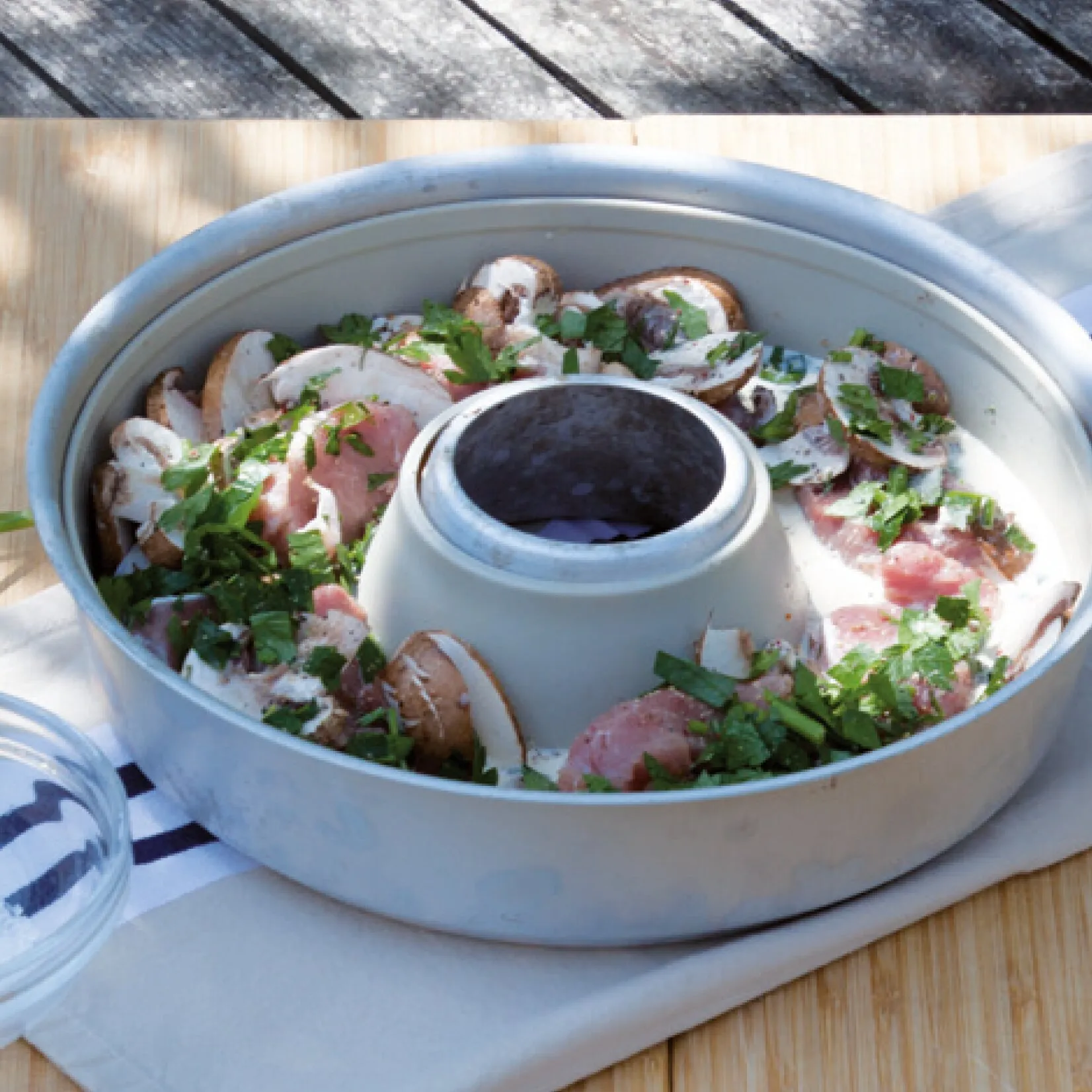 Omnia-Backofen mit rohem Fleisch, Champignons, cremiger Sauce und gehackter Petersilie auf einem Holzbrett