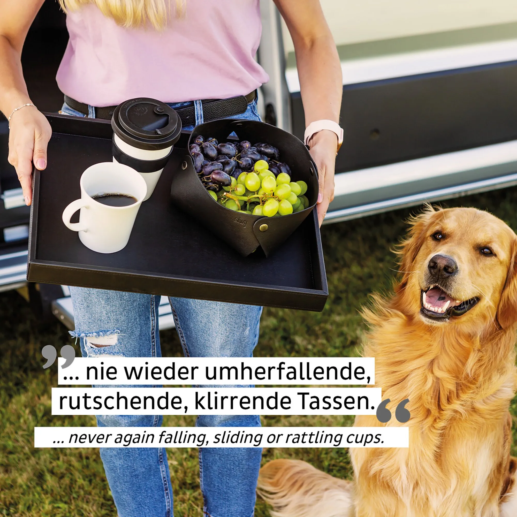 Frau trägt ein Tablett mit weißer Porzellantasse und Kaffee, weiterem Becher und Trauben neben einem Golden Retriever im Freien
